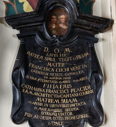 Zdjęcie nr 1: Epitafium w kształcie podwieszonej pod gzyms tkaniny. Gzyms profilowany, wybrzuszony półkoliście, z owalnym polem, w którym znajduje się portret zmarłych. Kobiety ukazane w popiersiu, w trzech czwartych, z oczami na wprost. Pod nim tablica z inskrypcją w kształcie podwieszonej zawiniętej na bokach tkaniny zakończonej motywem lambrekinu. W polu inskrypcja: „D(EO) O(PTIMO) M(AXIMO) / LAPIS HIC / MATREM SIMUL TEGIT  et FILIAM / MATER / FRANCISCA CUCHI VENETA / EMENSO IN PIETATE CATHOLICA. / 74. ANNORUM CURDU / IN VIAM AETERNITATIS 13.AUGU(STI) 1753 ABIIT. / FILIA EJUS / CATHARINA FRANCISCI PLACIDI / S(ACRE) R(EGIE) M(AIESTATIS) ARCHITECTI et CAPITANI CONJUNX / MATREM SUAM / 43 ANNIS IN VIRTUTIBUS IMITATA / 10 MAJI A(NNO) 1756 HUC SECUTA. / UTRAMQ VIATOR / PIIS AD DEUM VOTIS PROSEQUERE / et VALE”. 