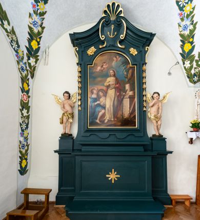 Zdjęcie nr 1: Ołtarz drewniany, jednoosiowy, jednokondygnacyjny. Mensa ołtarza z antepedium, w którym złocony krzyż. Nastawa ujęta postumentami z aniołami, w profilowanej ramie z kampanulami po bokach, z uszkami i konsolami w górnej części, zwieńczona bogato profilowanym wklęsłym gzymsem przechodzącym w dwie zwrócone ku sobie woluty z kartuszem i godłem Kotwica, umieszczonym pod muszlą palmetową. Obraz w ramie profilowanej, prostokątny, zamknięty półkolistym łukiem nadwieszonym. Stojące po bokach aniołki ukazane w kontrapoście, nagie, o pulchnych kształtach, przepasane na biodrach, z zarzuconymi na plecy złoconymi, miękko marszczonymi draperiami. Nastawa ciemnozielona ze złoconymi ornamentami i profilami; aniołki w naturalistycznej tonacji kolorystycznej. 
