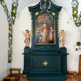 Zdjęcie nr 1: Ołtarz drewniany, jednoosiowy, jednokondygnacyjny. Mensa ołtarza z antepedium, w którym złocony krzyż. Nastawa ujęta postumentami z aniołami, w profilowanej ramie z kampanulami po bokach, z uszkami i konsolami w górnej części, zwieńczona bogato profilowanym wklęsłym gzymsem przechodzącym w dwie zwrócone ku sobie woluty z kartuszem i godłem Kotwica, umieszczonym pod muszlą palmetową. Obraz w ramie profilowanej, prostokątny, zamknięty półkolistym łukiem nadwieszonym. Stojące po bokach aniołki ukazane w kontrapoście, nagie, o pulchnych kształtach, przepasane na biodrach, z zarzuconymi na plecy złoconymi, miękko marszczonymi draperiami. Nastawa ciemnozielona ze złoconymi ornamentami i profilami; aniołki w naturalistycznej tonacji kolorystycznej. 
