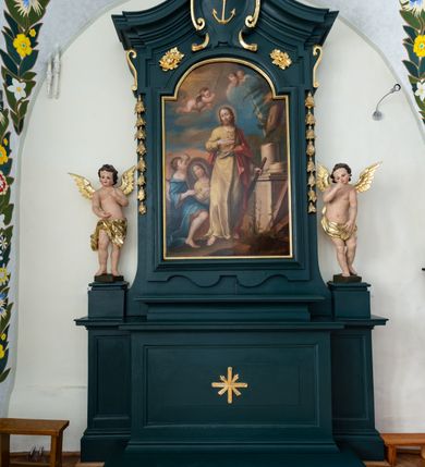 Zdjęcie nr 2: Ołtarz drewniany, jednoosiowy, jednokondygnacyjny. Mensa ołtarza z antepedium, w którym złocony krzyż. Nastawa ujęta postumentami z aniołami, w profilowanej ramie z kampanulami po bokach, z uszkami i konsolami w górnej części, zwieńczona bogato profilowanym wklęsłym gzymsem przechodzącym w dwie zwrócone ku sobie woluty z kartuszem i godłem Kotwica, umieszczonym pod muszlą palmetową. Obraz w ramie profilowanej, prostokątny, zamknięty półkolistym łukiem nadwieszonym. Stojące po bokach aniołki ukazane w kontrapoście, nagie, o pulchnych kształtach, przepasane na biodrach, z zarzuconymi na plecy złoconymi, miękko marszczonymi draperiami. Nastawa ciemnozielona ze złoconymi ornamentami i profilami; aniołki w naturalistycznej tonacji kolorystycznej. 
