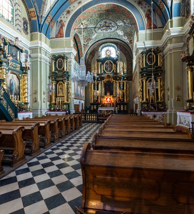 Zdjęcie nr 15: Kościół jest murowany z cegły, tynkowany, jednonawowy. Założony jest na rzucie prostokąta, z czteroprzęsłowym korpusem oraz jednoprzęsłowym prezbiterium, zamknięty prosto i skierowanym na południe. Ściana południowa wychodzi na ogród klasztorny, natomiast wschodnia i północna złączone są z klasztorem. Prezbiterium po obu stronach flankowane jest zakrystiami, nad którymi mieszczą się małe chóry. Chóry otwierają się do pojedynczymi arkadami do prezbiterium z drewnianymi balustradami. Do dwuprzęsłowej nawy od północy przylegają kolejne dwa przęsła korpusu, które stanowią kruchtę i kaplicę klasztoru, a nad nimi wzniesiony jest chór zakonny, oddzielony kratą. Nawa artykułowana jest za pomocą zdwojonych filarów, dźwigających wydatne belkowanie i tworzących półkoliście zamknięte wnęki arkadowe na ołtarze. Korpus kościoła sklepiony jest kolebkowo z lunetami na gurtach, natomiast w prezbiterium i kruchcie znajdują się sklepienia krzyżowe. Ściana arkady tęczowej zamknięta jest półkoliście. Wnętrze kościoła doświetlają umieszczone ponad belkowaniem okna w kształcie stojących prostokątów, zamknięte półkoliście. Do kościoła prowadzą drzwi wejściowe od północy przez kruchtę, do której wejście znajduje się od zachodu przez dziedziniec. Kolejne dwa wejścia prowadzą od strony klasztory przez kruchtę i zakrystię. Fasada północna kościoła wtopiona jest w bryłę klasztoru. Od strony dziedzińca, prowadzącego do głównego wejścia widoczna jest strona zachodnia kościoła, artykułowa zdwojonymi pilastrami. Portal główny flankowany jest kolumnami na tle pilastrów, które podtrzymują belkowanie i przerwany półkoliście zamknięty przyczółek. Podpory wsparte są na wysokich cokołach. Drzwi wejściowe flankuje półkoliście zamknięta arkada wsparta na parze filarów. Kościół nakrywa dach siodłowy, nad drugim przęsłem korpusu od strony północnej znajduje się wieżyczka na sygnaturkę ze zdwojoną latarnią. Przed kościołem znajduje się dziedziniec oddzielony od ulicy klasycystycznym murem z bramą.