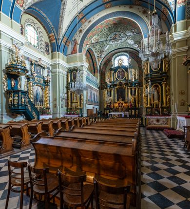 Zdjęcie nr 14: Kościół jest murowany z cegły, tynkowany, jednonawowy. Założony jest na rzucie prostokąta, z czteroprzęsłowym korpusem oraz jednoprzęsłowym prezbiterium, zamknięty prosto i skierowanym na południe. Ściana południowa wychodzi na ogród klasztorny, natomiast wschodnia i północna złączone są z klasztorem. Prezbiterium po obu stronach flankowane jest zakrystiami, nad którymi mieszczą się małe chóry. Chóry otwierają się do pojedynczymi arkadami do prezbiterium z drewnianymi balustradami. Do dwuprzęsłowej nawy od północy przylegają kolejne dwa przęsła korpusu, które stanowią kruchtę i kaplicę klasztoru, a nad nimi wzniesiony jest chór zakonny, oddzielony kratą. Nawa artykułowana jest za pomocą zdwojonych filarów, dźwigających wydatne belkowanie i tworzących półkoliście zamknięte wnęki arkadowe na ołtarze. Korpus kościoła sklepiony jest kolebkowo z lunetami na gurtach, natomiast w prezbiterium i kruchcie znajdują się sklepienia krzyżowe. Ściana arkady tęczowej zamknięta jest półkoliście. Wnętrze kościoła doświetlają umieszczone ponad belkowaniem okna w kształcie stojących prostokątów, zamknięte półkoliście. Do kościoła prowadzą drzwi wejściowe od północy przez kruchtę, do której wejście znajduje się od zachodu przez dziedziniec. Kolejne dwa wejścia prowadzą od strony klasztory przez kruchtę i zakrystię. Fasada północna kościoła wtopiona jest w bryłę klasztoru. Od strony dziedzińca, prowadzącego do głównego wejścia widoczna jest strona zachodnia kościoła, artykułowa zdwojonymi pilastrami. Portal główny flankowany jest kolumnami na tle pilastrów, które podtrzymują belkowanie i przerwany półkoliście zamknięty przyczółek. Podpory wsparte są na wysokich cokołach. Drzwi wejściowe flankuje półkoliście zamknięta arkada wsparta na parze filarów. Kościół nakrywa dach siodłowy, nad drugim przęsłem korpusu od strony północnej znajduje się wieżyczka na sygnaturkę ze zdwojoną latarnią. Przed kościołem znajduje się dziedziniec oddzielony od ulicy klasycystycznym murem z bramą.