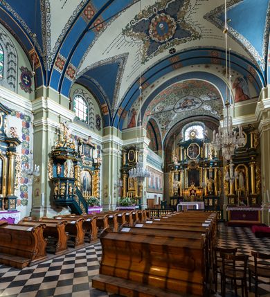 Zdjęcie nr 18: Kościół jest murowany z cegły, tynkowany, jednonawowy. Założony jest na rzucie prostokąta, z czteroprzęsłowym korpusem oraz jednoprzęsłowym prezbiterium, zamknięty prosto i skierowanym na południe. Ściana południowa wychodzi na ogród klasztorny, natomiast wschodnia i północna złączone są z klasztorem. Prezbiterium po obu stronach flankowane jest zakrystiami, nad którymi mieszczą się małe chóry. Chóry otwierają się do pojedynczymi arkadami do prezbiterium z drewnianymi balustradami. Do dwuprzęsłowej nawy od północy przylegają kolejne dwa przęsła korpusu, które stanowią kruchtę i kaplicę klasztoru, a nad nimi wzniesiony jest chór zakonny, oddzielony kratą. Nawa artykułowana jest za pomocą zdwojonych filarów, dźwigających wydatne belkowanie i tworzących półkoliście zamknięte wnęki arkadowe na ołtarze. Korpus kościoła sklepiony jest kolebkowo z lunetami na gurtach, natomiast w prezbiterium i kruchcie znajdują się sklepienia krzyżowe. Ściana arkady tęczowej zamknięta jest półkoliście. Wnętrze kościoła doświetlają umieszczone ponad belkowaniem okna w kształcie stojących prostokątów, zamknięte półkoliście. Do kościoła prowadzą drzwi wejściowe od północy przez kruchtę, do której wejście znajduje się od zachodu przez dziedziniec. Kolejne dwa wejścia prowadzą od strony klasztory przez kruchtę i zakrystię. Fasada północna kościoła wtopiona jest w bryłę klasztoru. Od strony dziedzińca, prowadzącego do głównego wejścia widoczna jest strona zachodnia kościoła, artykułowa zdwojonymi pilastrami. Portal główny flankowany jest kolumnami na tle pilastrów, które podtrzymują belkowanie i przerwany półkoliście zamknięty przyczółek. Podpory wsparte są na wysokich cokołach. Drzwi wejściowe flankuje półkoliście zamknięta arkada wsparta na parze filarów. Kościół nakrywa dach siodłowy, nad drugim przęsłem korpusu od strony północnej znajduje się wieżyczka na sygnaturkę ze zdwojoną latarnią. Przed kościołem znajduje się dziedziniec oddzielony od ulicy klasycystycznym murem z bramą.