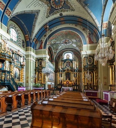 Zdjęcie nr 17: Kościół jest murowany z cegły, tynkowany, jednonawowy. Założony jest na rzucie prostokąta, z czteroprzęsłowym korpusem oraz jednoprzęsłowym prezbiterium, zamknięty prosto i skierowanym na południe. Ściana południowa wychodzi na ogród klasztorny, natomiast wschodnia i północna złączone są z klasztorem. Prezbiterium po obu stronach flankowane jest zakrystiami, nad którymi mieszczą się małe chóry. Chóry otwierają się do pojedynczymi arkadami do prezbiterium z drewnianymi balustradami. Do dwuprzęsłowej nawy od północy przylegają kolejne dwa przęsła korpusu, które stanowią kruchtę i kaplicę klasztoru, a nad nimi wzniesiony jest chór zakonny, oddzielony kratą. Nawa artykułowana jest za pomocą zdwojonych filarów, dźwigających wydatne belkowanie i tworzących półkoliście zamknięte wnęki arkadowe na ołtarze. Korpus kościoła sklepiony jest kolebkowo z lunetami na gurtach, natomiast w prezbiterium i kruchcie znajdują się sklepienia krzyżowe. Ściana arkady tęczowej zamknięta jest półkoliście. Wnętrze kościoła doświetlają umieszczone ponad belkowaniem okna w kształcie stojących prostokątów, zamknięte półkoliście. Do kościoła prowadzą drzwi wejściowe od północy przez kruchtę, do której wejście znajduje się od zachodu przez dziedziniec. Kolejne dwa wejścia prowadzą od strony klasztory przez kruchtę i zakrystię. Fasada północna kościoła wtopiona jest w bryłę klasztoru. Od strony dziedzińca, prowadzącego do głównego wejścia widoczna jest strona zachodnia kościoła, artykułowa zdwojonymi pilastrami. Portal główny flankowany jest kolumnami na tle pilastrów, które podtrzymują belkowanie i przerwany półkoliście zamknięty przyczółek. Podpory wsparte są na wysokich cokołach. Drzwi wejściowe flankuje półkoliście zamknięta arkada wsparta na parze filarów. Kościół nakrywa dach siodłowy, nad drugim przęsłem korpusu od strony północnej znajduje się wieżyczka na sygnaturkę ze zdwojoną latarnią. Przed kościołem znajduje się dziedziniec oddzielony od ulicy klasycystycznym murem z bramą.