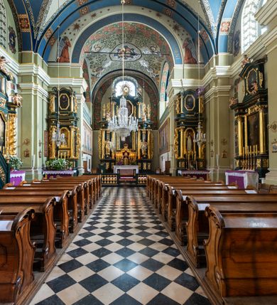 Zdjęcie nr 16: Kościół jest murowany z cegły, tynkowany, jednonawowy. Założony jest na rzucie prostokąta, z czteroprzęsłowym korpusem oraz jednoprzęsłowym prezbiterium, zamknięty prosto i skierowanym na południe. Ściana południowa wychodzi na ogród klasztorny, natomiast wschodnia i północna złączone są z klasztorem. Prezbiterium po obu stronach flankowane jest zakrystiami, nad którymi mieszczą się małe chóry. Chóry otwierają się do pojedynczymi arkadami do prezbiterium z drewnianymi balustradami. Do dwuprzęsłowej nawy od północy przylegają kolejne dwa przęsła korpusu, które stanowią kruchtę i kaplicę klasztoru, a nad nimi wzniesiony jest chór zakonny, oddzielony kratą. Nawa artykułowana jest za pomocą zdwojonych filarów, dźwigających wydatne belkowanie i tworzących półkoliście zamknięte wnęki arkadowe na ołtarze. Korpus kościoła sklepiony jest kolebkowo z lunetami na gurtach, natomiast w prezbiterium i kruchcie znajdują się sklepienia krzyżowe. Ściana arkady tęczowej zamknięta jest półkoliście. Wnętrze kościoła doświetlają umieszczone ponad belkowaniem okna w kształcie stojących prostokątów, zamknięte półkoliście. Do kościoła prowadzą drzwi wejściowe od północy przez kruchtę, do której wejście znajduje się od zachodu przez dziedziniec. Kolejne dwa wejścia prowadzą od strony klasztory przez kruchtę i zakrystię. Fasada północna kościoła wtopiona jest w bryłę klasztoru. Od strony dziedzińca, prowadzącego do głównego wejścia widoczna jest strona zachodnia kościoła, artykułowa zdwojonymi pilastrami. Portal główny flankowany jest kolumnami na tle pilastrów, które podtrzymują belkowanie i przerwany półkoliście zamknięty przyczółek. Podpory wsparte są na wysokich cokołach. Drzwi wejściowe flankuje półkoliście zamknięta arkada wsparta na parze filarów. Kościół nakrywa dach siodłowy, nad drugim przęsłem korpusu od strony północnej znajduje się wieżyczka na sygnaturkę ze zdwojoną latarnią. Przed kościołem znajduje się dziedziniec oddzielony od ulicy klasycystycznym murem z bramą.