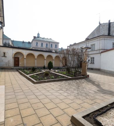 Zdjęcie nr 2: Kościół jest murowany z cegły, tynkowany, jednonawowy. Założony jest na rzucie prostokąta, z czteroprzęsłowym korpusem oraz jednoprzęsłowym prezbiterium, zamknięty prosto i skierowanym na południe. Ściana południowa wychodzi na ogród klasztorny, natomiast wschodnia i północna złączone są z klasztorem. Prezbiterium po obu stronach flankowane jest zakrystiami, nad którymi mieszczą się małe chóry. Chóry otwierają się do pojedynczymi arkadami do prezbiterium z drewnianymi balustradami. Do dwuprzęsłowej nawy od północy przylegają kolejne dwa przęsła korpusu, które stanowią kruchtę i kaplicę klasztoru, a nad nimi wzniesiony jest chór zakonny, oddzielony kratą. Nawa artykułowana jest za pomocą zdwojonych filarów, dźwigających wydatne belkowanie i tworzących półkoliście zamknięte wnęki arkadowe na ołtarze. Korpus kościoła sklepiony jest kolebkowo z lunetami na gurtach, natomiast w prezbiterium i kruchcie znajdują się sklepienia krzyżowe. Ściana arkady tęczowej zamknięta jest półkoliście. Wnętrze kościoła doświetlają umieszczone ponad belkowaniem okna w kształcie stojących prostokątów, zamknięte półkoliście. Do kościoła prowadzą drzwi wejściowe od północy przez kruchtę, do której wejście znajduje się od zachodu przez dziedziniec. Kolejne dwa wejścia prowadzą od strony klasztory przez kruchtę i zakrystię. Fasada północna kościoła wtopiona jest w bryłę klasztoru. Od strony dziedzińca, prowadzącego do głównego wejścia widoczna jest strona zachodnia kościoła, artykułowa zdwojonymi pilastrami. Portal główny flankowany jest kolumnami na tle pilastrów, które podtrzymują belkowanie i przerwany półkoliście zamknięty przyczółek. Podpory wsparte są na wysokich cokołach. Drzwi wejściowe flankuje półkoliście zamknięta arkada wsparta na parze filarów. Kościół nakrywa dach siodłowy, nad drugim przęsłem korpusu od strony północnej znajduje się wieżyczka na sygnaturkę ze zdwojoną latarnią. Przed kościołem znajduje się dziedziniec oddzielony od ulicy klasycystycznym murem z bramą.