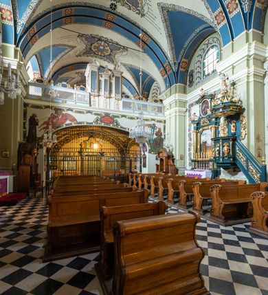 Zdjęcie nr 23: Kościół jest murowany z cegły, tynkowany, jednonawowy. Założony jest na rzucie prostokąta, z czteroprzęsłowym korpusem oraz jednoprzęsłowym prezbiterium, zamknięty prosto i skierowanym na południe. Ściana południowa wychodzi na ogród klasztorny, natomiast wschodnia i północna złączone są z klasztorem. Prezbiterium po obu stronach flankowane jest zakrystiami, nad którymi mieszczą się małe chóry. Chóry otwierają się do pojedynczymi arkadami do prezbiterium z drewnianymi balustradami. Do dwuprzęsłowej nawy od północy przylegają kolejne dwa przęsła korpusu, które stanowią kruchtę i kaplicę klasztoru, a nad nimi wzniesiony jest chór zakonny, oddzielony kratą. Nawa artykułowana jest za pomocą zdwojonych filarów, dźwigających wydatne belkowanie i tworzących półkoliście zamknięte wnęki arkadowe na ołtarze. Korpus kościoła sklepiony jest kolebkowo z lunetami na gurtach, natomiast w prezbiterium i kruchcie znajdują się sklepienia krzyżowe. Ściana arkady tęczowej zamknięta jest półkoliście. Wnętrze kościoła doświetlają umieszczone ponad belkowaniem okna w kształcie stojących prostokątów, zamknięte półkoliście. Do kościoła prowadzą drzwi wejściowe od północy przez kruchtę, do której wejście znajduje się od zachodu przez dziedziniec. Kolejne dwa wejścia prowadzą od strony klasztory przez kruchtę i zakrystię. Fasada północna kościoła wtopiona jest w bryłę klasztoru. Od strony dziedzińca, prowadzącego do głównego wejścia widoczna jest strona zachodnia kościoła, artykułowa zdwojonymi pilastrami. Portal główny flankowany jest kolumnami na tle pilastrów, które podtrzymują belkowanie i przerwany półkoliście zamknięty przyczółek. Podpory wsparte są na wysokich cokołach. Drzwi wejściowe flankuje półkoliście zamknięta arkada wsparta na parze filarów. Kościół nakrywa dach siodłowy, nad drugim przęsłem korpusu od strony północnej znajduje się wieżyczka na sygnaturkę ze zdwojoną latarnią. Przed kościołem znajduje się dziedziniec oddzielony od ulicy klasycystycznym murem z bramą.