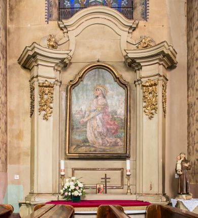 Zdjęcie nr 1: Ołtarz architektoniczny, drewniany, jednoosiowy, jednokondygnacyjny ze zwieńczeniem. Profilowana mensa w typie sarkofagowym na niskim, prostopadłym cokole, zakończona gzymsem. Część środkowa nastawy ujęta dwoma wklęsłowypukłymi, opilastrowanymi, ustawionymi skośnie podporami zwieńczonymi fragmentami pełnego belkowania z wydatnym gzymsem. Trzony pilastrów zdobione u góry nakładanym ornamentem rocaille'owym. W polu centralnym prostokątna płycina ze złoconą ramą, nad nią prostokątny obraz, zamknięty łukiem nadwieszonym z uskokiem przedstawiający św. Barbarę. Zwieńczenie zakończone gzymsem w kształcie łuku wklęsło-wypukłego, flankowane spływami dekorowanymi ornamentem rocaille’owym. Struktura polichromowana na kolor szary, profile i ornamenty złocone. 