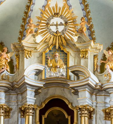 Zdjęcie nr 8: Nastawa ołtarzowa architektoniczna, jednoosiowa, dwukondygnacyjna ze zwieńczeniem. Mensa sarkofagowa, na niej tabernakulum w kształcie prostopadłościennej skrzynki na profilowanym cokole. Drzwiczki w formie stojącego prostokąta dekorowanego kielichem z hostią w glorii adorowaną przez klęczące anioły. Na nim ustawiono krucyfiks. Nastawa ołtarzowa na cokole, flankowana parami kolumn kompozytowych na tle pilastrów. Wewnętrzne kolumny ustawiono ukosem do wewnątrz, zewnętrzne na zewnątrz. Podpory  dźwigają fragmenty rozbudowanego belkowania o różnym wykroju ponad nimi i uwypuklającego się ponad polem centralnym. Wypełnia je nisza w kształcie stojącego prostokąta z uszakami, zamkniętego od góry łukiem nadwieszonym z uskokami. W niej znajduje się obraz z przedstawieniem św. Marcina w profilowanej, złoconej ramie.  Wewnętrzne podpory dźwigają fragmenty przerwanego przyczółka. Druga kondygnacja ma półokrągły wykrój, jest flankowana zwielokrotnionymi pilastrami   dekorowanymi płonącym rocaille’m i podtrzymującymi niewielkie spływy wolutowe, na których usadowiono putta. Pilastry ujmują spływy opierające się na zewnętrznych podporach niższej kondygnacji; na nich ustawiono figury aniołów.  Pole kondygnacji wypełnia nisza w kształcie stojącego prostokąta zamkniętego od góry łukiem nadwieszonym z uskokami wypełniona płaskorzeźbą Boga Ojca  pośród obłoków. Zwieńczenie tworzy rzeźba gołębicy Ducha Świętego w otoczeniu obłoków dekorowanych główkami anielskimi i w glorii promienistej. 
Struktura marmoryzowana w kolorze jasnoszarym; ornamentyka, profile, kolumny i detale złocone i srebrzone.