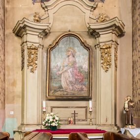 Zdjęcie nr 1: Obraz w formie stojącego prostokąta, zwieńczonego łukiem nadwieszonym z uskokiem, przedstawiający św. Barbarę. Święta ukazana w ujęciu całopostaciowym, zwrócona w trzech czwartych w prawo, klęczy z dłońmi splecionymi w geście modlitwy. U jej stóp  leżą miecz i palma męczeństwa. Ma twarz o rysach młodej dziewczyny, lekko uniesioną ku górze, wzrok skierowany ku niebu. Postać jest ubrana w białą suknię, na którą ma nałożoną jasnoróżową, przewiązaną w pasie niebieskim pasem i przechodzącą w rozwiany, czerwony płaszcz; spod niej widoczne są żółte rękawy. Na głowie ma biały zawój odsłaniający są ciemne, kręcone włosy opadające na plecy i ramiona. Na głowie ma koronę otoczoną promienistym nimbem. W tle sceny pejzaż, w którym między drzewami, po lewej stronie widnieje kościół (jednowieżowy, murowany; uważany za widok kościoła w Porębie Żegocie przed przebudową dokonaną przez Zygmunta Hendla). Po stronie prawej widoczna jest masywna baszta za murem krenelażowym. Przed basztą ukazano scenę męczeństwa świętej ścinanej toporem. Obraz utrzymany w jasnej, ciepłej kolorystyce, oprawiony w złoconą, profilowaną ramę.

