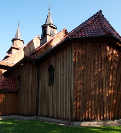 Zdjęcie nr 5: Kościół drewniany na podmurówce z kamienia, o konstrukcji zrębowej, szalowany; jednonawowy, orientowany; wieża o konstrukcji słupowej.
Prezbiterium na planie prostokąta zamkniętego trójbocznie, od północy przylega prostokątna w rzucie zakrystia; nawa na planie prostokąta, z przylegającą od południa kruchtą na rzucie kwadratu; dobudowana nawa na planie dłuższego od poprzedniej prostokąta, od zachodu wieża na planie kwadratu, częściowo wtopiona w ścianę zamykającą nawę, z wyodrębnionymi dwoma pomieszczeniami flankującymi ją.
Nawy i prezbiterium nakryte stropami, oddzielone od siebie szerokimi arkadami zamkniętymi łukami odcinkowymi. W zachodniej części większej nawy prosty parapet chóru muzycznego wsparty na dwóch drewnianych filarach; prospekt organowy przepruwa strop w przestrzeń wieży. Posadzka z płyt ceramicznych. Otwory okienne w formie stojącego prostokąta zamkniętego łukiem półkolistym, obwiedzione listwowymi opaskami, z kwaterowymi podziałami; od strony południowej – jedno w prezbiterium i po dwa w każdej części nawy, od strony północnej po dwa w każdej części nawy, od zachodniej dwa niewielkie flankujące wieżę. W zakrystii analogiczny otwór okienny od wschodu i mniejszy od północy. Otwory wejściowe: z prezbiterium do zakrystii drzwi płycinowe w futrynie; w przejściu z mniejszej nawy do kruchty drzwi płycinowe w futrynie; w przejściu z przyziemia wieży do większej nawy otwór w formie stojącego prostokąta z wklęsłymi górnymi narożami, obwiedziony listwowymi opaskami. 
Ściany z zewnątrz szalowane z listwowaniem. Trzy dachy z osobnymi kalenicami, nad prezbiterium wielospadowy; nad dwiema nawami dwuspadowe, zakończone daszkami okapowymi; kryte ceramiczną dachówką. Wieżyczka na sygnaturkę na kalenicy nad mniejszą nawą, obita blachą, zamknięta daszkiem wieżowym. 
Wieża o ścianach zwężających się ku górze, trójkondygnacyjna. Dolna kondygnacja zamknięta gzymsem, a dwie wyższe daszkami okapowymi. Całość zwieńczona hełmem ostrosłupowym z latarnią przeprutą oknami. Otwory okienne: w pierwszej kondygnacji na ścianie wschodniej i zachodniej w formie stojącego prostokąta zamkniętego łukiem półkolistym, obwiedzione listwowymi opaskami, z kwaterowymi podziałami; w drugiej kondygnacji z trzech stron okulusy, w trzeciej z czterech stron niewielkie okienka. Otwór wejściowy od zachodu, na pięciu kamiennych stopniach, drzwi deskowe-spągowe, dwuskrzydłowe, w odrzwiach belkowych; nakryty daszkiem dwuspadowym.
