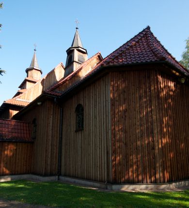 Zdjęcie nr 4: Kościół drewniany na podmurówce z kamienia, o konstrukcji zrębowej, szalowany; jednonawowy, orientowany; wieża o konstrukcji słupowej.
Prezbiterium na planie prostokąta zamkniętego trójbocznie, od północy przylega prostokątna w rzucie zakrystia; nawa na planie prostokąta, z przylegającą od południa kruchtą na rzucie kwadratu; dobudowana nawa na planie dłuższego od poprzedniej prostokąta, od zachodu wieża na planie kwadratu, częściowo wtopiona w ścianę zamykającą nawę, z wyodrębnionymi dwoma pomieszczeniami flankującymi ją.
Nawy i prezbiterium nakryte stropami, oddzielone od siebie szerokimi arkadami zamkniętymi łukami odcinkowymi. W zachodniej części większej nawy prosty parapet chóru muzycznego wsparty na dwóch drewnianych filarach; prospekt organowy przepruwa strop w przestrzeń wieży. Posadzka z płyt ceramicznych. Otwory okienne w formie stojącego prostokąta zamkniętego łukiem półkolistym, obwiedzione listwowymi opaskami, z kwaterowymi podziałami; od strony południowej – jedno w prezbiterium i po dwa w każdej części nawy, od strony północnej po dwa w każdej części nawy, od zachodniej dwa niewielkie flankujące wieżę. W zakrystii analogiczny otwór okienny od wschodu i mniejszy od północy. Otwory wejściowe: z prezbiterium do zakrystii drzwi płycinowe w futrynie; w przejściu z mniejszej nawy do kruchty drzwi płycinowe w futrynie; w przejściu z przyziemia wieży do większej nawy otwór w formie stojącego prostokąta z wklęsłymi górnymi narożami, obwiedziony listwowymi opaskami. 
Ściany z zewnątrz szalowane z listwowaniem. Trzy dachy z osobnymi kalenicami, nad prezbiterium wielospadowy; nad dwiema nawami dwuspadowe, zakończone daszkami okapowymi; kryte ceramiczną dachówką. Wieżyczka na sygnaturkę na kalenicy nad mniejszą nawą, obita blachą, zamknięta daszkiem wieżowym. 
Wieża o ścianach zwężających się ku górze, trójkondygnacyjna. Dolna kondygnacja zamknięta gzymsem, a dwie wyższe daszkami okapowymi. Całość zwieńczona hełmem ostrosłupowym z latarnią przeprutą oknami. Otwory okienne: w pierwszej kondygnacji na ścianie wschodniej i zachodniej w formie stojącego prostokąta zamkniętego łukiem półkolistym, obwiedzione listwowymi opaskami, z kwaterowymi podziałami; w drugiej kondygnacji z trzech stron okulusy, w trzeciej z czterech stron niewielkie okienka. Otwór wejściowy od zachodu, na pięciu kamiennych stopniach, drzwi deskowe-spągowe, dwuskrzydłowe, w odrzwiach belkowych; nakryty daszkiem dwuspadowym.
