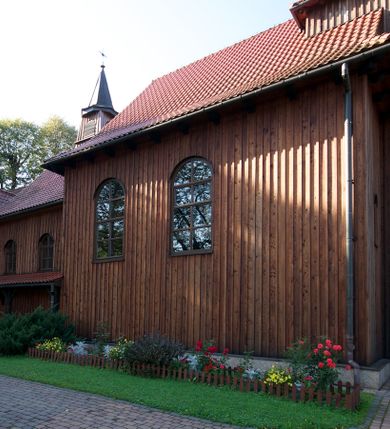 Zdjęcie nr 11: Kościół drewniany na podmurówce z kamienia, o konstrukcji zrębowej, szalowany; jednonawowy, orientowany; wieża o konstrukcji słupowej.
Prezbiterium na planie prostokąta zamkniętego trójbocznie, od północy przylega prostokątna w rzucie zakrystia; nawa na planie prostokąta, z przylegającą od południa kruchtą na rzucie kwadratu; dobudowana nawa na planie dłuższego od poprzedniej prostokąta, od zachodu wieża na planie kwadratu, częściowo wtopiona w ścianę zamykającą nawę, z wyodrębnionymi dwoma pomieszczeniami flankującymi ją.
Nawy i prezbiterium nakryte stropami, oddzielone od siebie szerokimi arkadami zamkniętymi łukami odcinkowymi. W zachodniej części większej nawy prosty parapet chóru muzycznego wsparty na dwóch drewnianych filarach; prospekt organowy przepruwa strop w przestrzeń wieży. Posadzka z płyt ceramicznych. Otwory okienne w formie stojącego prostokąta zamkniętego łukiem półkolistym, obwiedzione listwowymi opaskami, z kwaterowymi podziałami; od strony południowej – jedno w prezbiterium i po dwa w każdej części nawy, od strony północnej po dwa w każdej części nawy, od zachodniej dwa niewielkie flankujące wieżę. W zakrystii analogiczny otwór okienny od wschodu i mniejszy od północy. Otwory wejściowe: z prezbiterium do zakrystii drzwi płycinowe w futrynie; w przejściu z mniejszej nawy do kruchty drzwi płycinowe w futrynie; w przejściu z przyziemia wieży do większej nawy otwór w formie stojącego prostokąta z wklęsłymi górnymi narożami, obwiedziony listwowymi opaskami. 
Ściany z zewnątrz szalowane z listwowaniem. Trzy dachy z osobnymi kalenicami, nad prezbiterium wielospadowy; nad dwiema nawami dwuspadowe, zakończone daszkami okapowymi; kryte ceramiczną dachówką. Wieżyczka na sygnaturkę na kalenicy nad mniejszą nawą, obita blachą, zamknięta daszkiem wieżowym. 
Wieża o ścianach zwężających się ku górze, trójkondygnacyjna. Dolna kondygnacja zamknięta gzymsem, a dwie wyższe daszkami okapowymi. Całość zwieńczona hełmem ostrosłupowym z latarnią przeprutą oknami. Otwory okienne: w pierwszej kondygnacji na ścianie wschodniej i zachodniej w formie stojącego prostokąta zamkniętego łukiem półkolistym, obwiedzione listwowymi opaskami, z kwaterowymi podziałami; w drugiej kondygnacji z trzech stron okulusy, w trzeciej z czterech stron niewielkie okienka. Otwór wejściowy od zachodu, na pięciu kamiennych stopniach, drzwi deskowe-spągowe, dwuskrzydłowe, w odrzwiach belkowych; nakryty daszkiem dwuspadowym.
