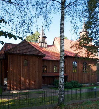 Zdjęcie nr 13: Kościół drewniany na podmurówce z kamienia, o konstrukcji zrębowej, szalowany; jednonawowy, orientowany; wieża o konstrukcji słupowej.
Prezbiterium na planie prostokąta zamkniętego trójbocznie, od północy przylega prostokątna w rzucie zakrystia; nawa na planie prostokąta, z przylegającą od południa kruchtą na rzucie kwadratu; dobudowana nawa na planie dłuższego od poprzedniej prostokąta, od zachodu wieża na planie kwadratu, częściowo wtopiona w ścianę zamykającą nawę, z wyodrębnionymi dwoma pomieszczeniami flankującymi ją.
Nawy i prezbiterium nakryte stropami, oddzielone od siebie szerokimi arkadami zamkniętymi łukami odcinkowymi. W zachodniej części większej nawy prosty parapet chóru muzycznego wsparty na dwóch drewnianych filarach; prospekt organowy przepruwa strop w przestrzeń wieży. Posadzka z płyt ceramicznych. Otwory okienne w formie stojącego prostokąta zamkniętego łukiem półkolistym, obwiedzione listwowymi opaskami, z kwaterowymi podziałami; od strony południowej – jedno w prezbiterium i po dwa w każdej części nawy, od strony północnej po dwa w każdej części nawy, od zachodniej dwa niewielkie flankujące wieżę. W zakrystii analogiczny otwór okienny od wschodu i mniejszy od północy. Otwory wejściowe: z prezbiterium do zakrystii drzwi płycinowe w futrynie; w przejściu z mniejszej nawy do kruchty drzwi płycinowe w futrynie; w przejściu z przyziemia wieży do większej nawy otwór w formie stojącego prostokąta z wklęsłymi górnymi narożami, obwiedziony listwowymi opaskami. 
Ściany z zewnątrz szalowane z listwowaniem. Trzy dachy z osobnymi kalenicami, nad prezbiterium wielospadowy; nad dwiema nawami dwuspadowe, zakończone daszkami okapowymi; kryte ceramiczną dachówką. Wieżyczka na sygnaturkę na kalenicy nad mniejszą nawą, obita blachą, zamknięta daszkiem wieżowym. 
Wieża o ścianach zwężających się ku górze, trójkondygnacyjna. Dolna kondygnacja zamknięta gzymsem, a dwie wyższe daszkami okapowymi. Całość zwieńczona hełmem ostrosłupowym z latarnią przeprutą oknami. Otwory okienne: w pierwszej kondygnacji na ścianie wschodniej i zachodniej w formie stojącego prostokąta zamkniętego łukiem półkolistym, obwiedzione listwowymi opaskami, z kwaterowymi podziałami; w drugiej kondygnacji z trzech stron okulusy, w trzeciej z czterech stron niewielkie okienka. Otwór wejściowy od zachodu, na pięciu kamiennych stopniach, drzwi deskowe-spągowe, dwuskrzydłowe, w odrzwiach belkowych; nakryty daszkiem dwuspadowym.
