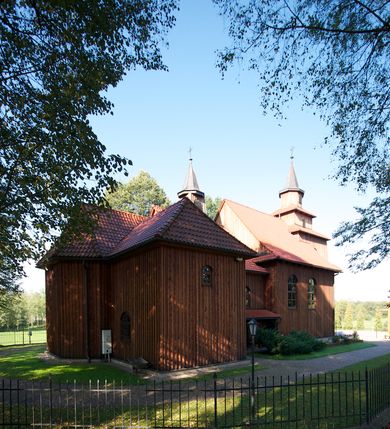 Zdjęcie nr 9: Kościół drewniany na podmurówce z kamienia, o konstrukcji zrębowej, szalowany; jednonawowy, orientowany; wieża o konstrukcji słupowej.
Prezbiterium na planie prostokąta zamkniętego trójbocznie, od północy przylega prostokątna w rzucie zakrystia; nawa na planie prostokąta, z przylegającą od południa kruchtą na rzucie kwadratu; dobudowana nawa na planie dłuższego od poprzedniej prostokąta, od zachodu wieża na planie kwadratu, częściowo wtopiona w ścianę zamykającą nawę, z wyodrębnionymi dwoma pomieszczeniami flankującymi ją.
Nawy i prezbiterium nakryte stropami, oddzielone od siebie szerokimi arkadami zamkniętymi łukami odcinkowymi. W zachodniej części większej nawy prosty parapet chóru muzycznego wsparty na dwóch drewnianych filarach; prospekt organowy przepruwa strop w przestrzeń wieży. Posadzka z płyt ceramicznych. Otwory okienne w formie stojącego prostokąta zamkniętego łukiem półkolistym, obwiedzione listwowymi opaskami, z kwaterowymi podziałami; od strony południowej – jedno w prezbiterium i po dwa w każdej części nawy, od strony północnej po dwa w każdej części nawy, od zachodniej dwa niewielkie flankujące wieżę. W zakrystii analogiczny otwór okienny od wschodu i mniejszy od północy. Otwory wejściowe: z prezbiterium do zakrystii drzwi płycinowe w futrynie; w przejściu z mniejszej nawy do kruchty drzwi płycinowe w futrynie; w przejściu z przyziemia wieży do większej nawy otwór w formie stojącego prostokąta z wklęsłymi górnymi narożami, obwiedziony listwowymi opaskami. 
Ściany z zewnątrz szalowane z listwowaniem. Trzy dachy z osobnymi kalenicami, nad prezbiterium wielospadowy; nad dwiema nawami dwuspadowe, zakończone daszkami okapowymi; kryte ceramiczną dachówką. Wieżyczka na sygnaturkę na kalenicy nad mniejszą nawą, obita blachą, zamknięta daszkiem wieżowym. 
Wieża o ścianach zwężających się ku górze, trójkondygnacyjna. Dolna kondygnacja zamknięta gzymsem, a dwie wyższe daszkami okapowymi. Całość zwieńczona hełmem ostrosłupowym z latarnią przeprutą oknami. Otwory okienne: w pierwszej kondygnacji na ścianie wschodniej i zachodniej w formie stojącego prostokąta zamkniętego łukiem półkolistym, obwiedzione listwowymi opaskami, z kwaterowymi podziałami; w drugiej kondygnacji z trzech stron okulusy, w trzeciej z czterech stron niewielkie okienka. Otwór wejściowy od zachodu, na pięciu kamiennych stopniach, drzwi deskowe-spągowe, dwuskrzydłowe, w odrzwiach belkowych; nakryty daszkiem dwuspadowym.
