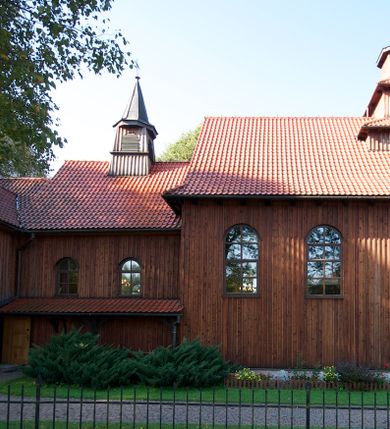 Zdjęcie nr 8: Kościół drewniany na podmurówce z kamienia, o konstrukcji zrębowej, szalowany; jednonawowy, orientowany; wieża o konstrukcji słupowej.
Prezbiterium na planie prostokąta zamkniętego trójbocznie, od północy przylega prostokątna w rzucie zakrystia; nawa na planie prostokąta, z przylegającą od południa kruchtą na rzucie kwadratu; dobudowana nawa na planie dłuższego od poprzedniej prostokąta, od zachodu wieża na planie kwadratu, częściowo wtopiona w ścianę zamykającą nawę, z wyodrębnionymi dwoma pomieszczeniami flankującymi ją.
Nawy i prezbiterium nakryte stropami, oddzielone od siebie szerokimi arkadami zamkniętymi łukami odcinkowymi. W zachodniej części większej nawy prosty parapet chóru muzycznego wsparty na dwóch drewnianych filarach; prospekt organowy przepruwa strop w przestrzeń wieży. Posadzka z płyt ceramicznych. Otwory okienne w formie stojącego prostokąta zamkniętego łukiem półkolistym, obwiedzione listwowymi opaskami, z kwaterowymi podziałami; od strony południowej – jedno w prezbiterium i po dwa w każdej części nawy, od strony północnej po dwa w każdej części nawy, od zachodniej dwa niewielkie flankujące wieżę. W zakrystii analogiczny otwór okienny od wschodu i mniejszy od północy. Otwory wejściowe: z prezbiterium do zakrystii drzwi płycinowe w futrynie; w przejściu z mniejszej nawy do kruchty drzwi płycinowe w futrynie; w przejściu z przyziemia wieży do większej nawy otwór w formie stojącego prostokąta z wklęsłymi górnymi narożami, obwiedziony listwowymi opaskami. 
Ściany z zewnątrz szalowane z listwowaniem. Trzy dachy z osobnymi kalenicami, nad prezbiterium wielospadowy; nad dwiema nawami dwuspadowe, zakończone daszkami okapowymi; kryte ceramiczną dachówką. Wieżyczka na sygnaturkę na kalenicy nad mniejszą nawą, obita blachą, zamknięta daszkiem wieżowym. 
Wieża o ścianach zwężających się ku górze, trójkondygnacyjna. Dolna kondygnacja zamknięta gzymsem, a dwie wyższe daszkami okapowymi. Całość zwieńczona hełmem ostrosłupowym z latarnią przeprutą oknami. Otwory okienne: w pierwszej kondygnacji na ścianie wschodniej i zachodniej w formie stojącego prostokąta zamkniętego łukiem półkolistym, obwiedzione listwowymi opaskami, z kwaterowymi podziałami; w drugiej kondygnacji z trzech stron okulusy, w trzeciej z czterech stron niewielkie okienka. Otwór wejściowy od zachodu, na pięciu kamiennych stopniach, drzwi deskowe-spągowe, dwuskrzydłowe, w odrzwiach belkowych; nakryty daszkiem dwuspadowym.
