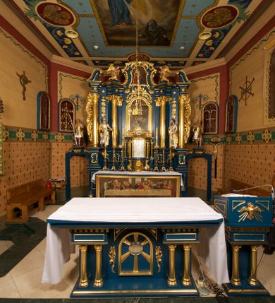 Zdjęcie nr 1: Ołtarz drewniany, prostopadłościenny, z kamienną mensą. Antepedium w formie obrazu z przedstawieniem Ostatniej Wieczerzy, ujętego profilowaną ramą. Na ołtarzu ustawione tabernakulum z tronem wystawienia. 
Nastawa architektoniczna, jednokondygnacyjna ze zwieńczeniem, trójosiowa z bramkami, ustawiona na dwustrefowym cokole z wyłamanymi czterema prostopadłościanami. Oś środkowa ujęta dwiema parami pilastrów oraz parą kolumn, na cokołach zwróconych pod kątem do wewnątrz ołtarza. Osie zewnętrzne ujęte parą pilastrów i stojących na ich tle kolumn. Wszystkie podpory dźwigają imposty, na osiach środkowy podpór zwrócone pod kątem do wewnątrz. Na parze skrajnych impostów fragmenty przerwanego, falistego przyczółka. W polu środkowym nisza w formie stojącego prostokąta zamkniętego łukiem półkolistym nadwieszonym, z uskokiem, ujęta profilowaną ramą, z obrazem Nauczania Marii. Na osiach bocznych figury św. Piotra i św. Pawła ustawione na wspornikach Zwieńczenie niearchitektoniczne, o formie zbliżonej do trapezu, o wklęsłych bokach z uszakami, zamknięte fragmentem falistego gzymsu. W polu obraz o fantazyjnej formie zbliżonej do trapezu z przedstawieniem św. Barbary, ujęty ornamentalną ramą. Zwieńczenie flankują dwie figury klęczących aniołów na cokołach. Nastawa dekorowana rocaille&#039;m w przestrzeni nad polem głównym oraz w partii zwieńczenia, ujęta uszami utworzonymi z rocaille&#039;u, kampanuli i ornamentu roślinnego. Na osiach bocznych zwisy kwiatowe. Bramki w formie przejść o wykroju stojącego prostokąta o wklęsłych górnych narożach, zamkniętego dwiema woltami i cokołami z imitacją puklowania, na których stoją figury niezidentyfikowanych monarchów. Struktura polichromowana w kolorze niebieskim, kolumny, profile i ornamentyka złocone. 






