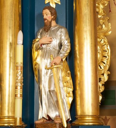 Zdjęcie nr 10: Ołtarz drewniany, prostopadłościenny, z kamienną mensą. Antepedium w formie obrazu z przedstawieniem Ostatniej Wieczerzy, ujętego profilowaną ramą. Na ołtarzu ustawione tabernakulum z tronem wystawienia. 
Nastawa architektoniczna, jednokondygnacyjna ze zwieńczeniem, trójosiowa z bramkami, ustawiona na dwustrefowym cokole z wyłamanymi czterema prostopadłościanami. Oś środkowa ujęta dwiema parami pilastrów oraz parą kolumn, na cokołach zwróconych pod kątem do wewnątrz ołtarza. Osie zewnętrzne ujęte parą pilastrów i stojących na ich tle kolumn. Wszystkie podpory dźwigają imposty, na osiach środkowy podpór zwrócone pod kątem do wewnątrz. Na parze skrajnych impostów fragmenty przerwanego, falistego przyczółka. W polu środkowym nisza w formie stojącego prostokąta zamkniętego łukiem półkolistym nadwieszonym, z uskokiem, ujęta profilowaną ramą, z obrazem Nauczania Marii. Na osiach bocznych figury św. Piotra i św. Pawła ustawione na wspornikach Zwieńczenie niearchitektoniczne, o formie zbliżonej do trapezu, o wklęsłych bokach z uszakami, zamknięte fragmentem falistego gzymsu. W polu obraz o fantazyjnej formie zbliżonej do trapezu z przedstawieniem św. Barbary, ujęty ornamentalną ramą. Zwieńczenie flankują dwie figury klęczących aniołów na cokołach. Nastawa dekorowana rocaille'm w przestrzeni nad polem głównym oraz w partii zwieńczenia, ujęta uszami utworzonymi z rocaille'u, kampanuli i ornamentu roślinnego. Na osiach bocznych zwisy kwiatowe. Bramki w formie przejść o wykroju stojącego prostokąta o wklęsłych górnych narożach, zamkniętego dwiema woltami i cokołami z imitacją puklowania, na których stoją figury niezidentyfikowanych monarchów. Struktura polichromowana w kolorze niebieskim, kolumny, profile i ornamentyka złocone. 






