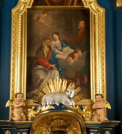 Zdjęcie nr 18: Ołtarz drewniany, prostopadłościenny, z kamienną mensą. Antepedium w formie obrazu z przedstawieniem Ostatniej Wieczerzy, ujętego profilowaną ramą. Na ołtarzu ustawione tabernakulum z tronem wystawienia. 
Nastawa architektoniczna, jednokondygnacyjna ze zwieńczeniem, trójosiowa z bramkami, ustawiona na dwustrefowym cokole z wyłamanymi czterema prostopadłościanami. Oś środkowa ujęta dwiema parami pilastrów oraz parą kolumn, na cokołach zwróconych pod kątem do wewnątrz ołtarza. Osie zewnętrzne ujęte parą pilastrów i stojących na ich tle kolumn. Wszystkie podpory dźwigają imposty, na osiach środkowy podpór zwrócone pod kątem do wewnątrz. Na parze skrajnych impostów fragmenty przerwanego, falistego przyczółka. W polu środkowym nisza w formie stojącego prostokąta zamkniętego łukiem półkolistym nadwieszonym, z uskokiem, ujęta profilowaną ramą, z obrazem Nauczania Marii. Na osiach bocznych figury św. Piotra i św. Pawła ustawione na wspornikach Zwieńczenie niearchitektoniczne, o formie zbliżonej do trapezu, o wklęsłych bokach z uszakami, zamknięte fragmentem falistego gzymsu. W polu obraz o fantazyjnej formie zbliżonej do trapezu z przedstawieniem św. Barbary, ujęty ornamentalną ramą. Zwieńczenie flankują dwie figury klęczących aniołów na cokołach. Nastawa dekorowana rocaille&#039;m w przestrzeni nad polem głównym oraz w partii zwieńczenia, ujęta uszami utworzonymi z rocaille&#039;u, kampanuli i ornamentu roślinnego. Na osiach bocznych zwisy kwiatowe. Bramki w formie przejść o wykroju stojącego prostokąta o wklęsłych górnych narożach, zamkniętego dwiema woltami i cokołami z imitacją puklowania, na których stoją figury niezidentyfikowanych monarchów. Struktura polichromowana w kolorze niebieskim, kolumny, profile i ornamentyka złocone. 






