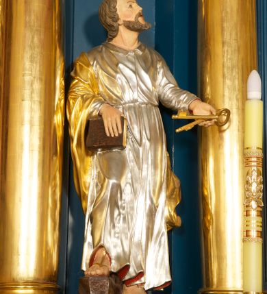 Zdjęcie nr 2: Rzeźba pełnoplastyczna, ustawiona na niskiej podstawie. Figura ukazana frontalnie, w lekkim odchyleniu, z uniesioną głową skierowaną w lewo. W lewej, wyciągniętej do przodu ręce trzyma skrzyżowane dwa klucze, w prawej, ugiętej ręce trzyma zamkniętą księgę, opartą na ugiętej nodze, ustawionej na stopniu. Twarz ma szeroką, o wysokim czole, niewielkich migdałowatych oczach, małych nosie i ustach. Włosy lekko kręcone, krótkie, silnie przylegające do głowy, z zaznaczoną łysiną i puklem nad czołem. Twarz okolona krótką, kręconą brodą z wąsami. Postać ubrana w długą, srebrzoną tunikę z kołnierzykiem, przepasaną w pasie oraz złocony płaszcz przerzucony przez prawe ramię i opadający na plecy. Na stopach ma złocone sandały. Polichromią ciała naturalistyczna. 






