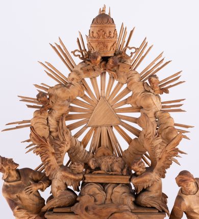 Zdjęcie nr 4: Tabernakulum w formie Arki Przymierza, adorowanej przez dwie klęczące figury św. Jana i starotestamentowego arcykapłana, dwie stojące postacie lewitów oraz klęczących aniołów, zwieńczonej glorią promienistą z okiem Opatrzności. Arka w formie prostopadłościennej szafki z dwoma drążkami do noszenia jest od frontu podzielone na trzy pola: środkowe zamknięte łukiem wklęsło-wypukłym i boczne o ćwierćkoliście wyciętych narożach. Pole środkowe stanowią drzwiczki z rytymi cyframi Dekalogu, a w bocznych znajdują się kłosy zbóż i winne grono. Na skłębionych chmurach z podestem leży baranek. Nad nim widnieje znacznej wielkości gloria promienista z wieńcem chmur i umieszczonym w nim okiem Opatrzności oraz cztery uskrzydlone główki anielskie. Nad parą główek w górnej części papieska tiara ze skrzyżowanymi kluczami. Po bokach baranka dwa klęczące, uskrzydlone nagie aniołki o rękach i nogach utworzonych z piór. Obok arki dwie postacie lewitów ubranych w długie szaty, w różnicowanych pozach i gestach. Poniżej klęczą postacie św. Jana z księgą i orłem obok niego i kapłana w tradycyjnym starotestamentowym stroju – efodzie czyli tunice i płaszczu wierzchnim przepasanym na biodrach, z pektorałem na piersi i czapką na głowie. 