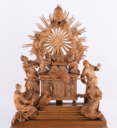Zdjęcie nr 1: Tabernakulum w formie Arki Przymierza, adorowanej przez dwie klęczące figury św. Jana i starotestamentowego arcykapłana, dwie stojące postacie lewitów oraz klęczących aniołów, zwieńczonej glorią promienistą z okiem Opatrzności. Arka w formie prostopadłościennej szafki z dwoma drążkami do noszenia jest od frontu podzielone na trzy pola: środkowe zamknięte łukiem wklęsło-wypukłym i boczne o ćwierćkoliście wyciętych narożach. Pole środkowe stanowią drzwiczki z rytymi cyframi Dekalogu, a w bocznych znajdują się kłosy zbóż i winne grono. Na skłębionych chmurach z podestem leży baranek. Nad nim widnieje znacznej wielkości gloria promienista z wieńcem chmur i umieszczonym w nim okiem Opatrzności oraz cztery uskrzydlone główki anielskie. Nad parą główek w górnej części papieska tiara ze skrzyżowanymi kluczami. Po bokach baranka dwa klęczące, uskrzydlone nagie aniołki o rękach i nogach utworzonych z piór. Obok arki dwie postacie lewitów ubranych w długie szaty, w różnicowanych pozach i gestach. Poniżej klęczą postacie św. Jana z księgą i orłem obok niego i kapłana w tradycyjnym starotestamentowym stroju – efodzie czyli tunice i płaszczu wierzchnim przepasanym na biodrach, z pektorałem na piersi i czapką na głowie. 