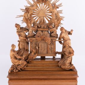 Zdjęcie nr 1: Tabernakulum w formie Arki Przymierza, adorowanej przez dwie klęczące figury św. Jana i starotestamentowego arcykapłana, dwie stojące postacie lewitów oraz klęczących aniołów, zwieńczonej glorią promienistą z okiem Opatrzności. Arka w formie prostopadłościennej szafki z dwoma drążkami do noszenia jest od frontu podzielone na trzy pola: środkowe zamknięte łukiem wklęsło-wypukłym i boczne o ćwierćkoliście wyciętych narożach. Pole środkowe stanowią drzwiczki z rytymi cyframi Dekalogu, a w bocznych znajdują się kłosy zbóż i winne grono. Na skłębionych chmurach z podestem leży baranek. Nad nim widnieje znacznej wielkości gloria promienista z wieńcem chmur i umieszczonym w nim okiem Opatrzności oraz cztery uskrzydlone główki anielskie. Nad parą główek w górnej części papieska tiara ze skrzyżowanymi kluczami. Po bokach baranka dwa klęczące, uskrzydlone nagie aniołki o rękach i nogach utworzonych z piór. Obok arki dwie postacie lewitów ubranych w długie szaty, w różnicowanych pozach i gestach. Poniżej klęczą postacie św. Jana z księgą i orłem obok niego i kapłana w tradycyjnym starotestamentowym stroju – efodzie czyli tunice i płaszczu wierzchnim przepasanym na biodrach, z pektorałem na piersi i czapką na głowie. 