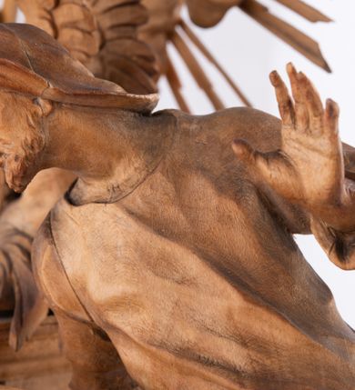 Zdjęcie nr 6: Tabernakulum w formie Arki Przymierza, adorowanej przez dwie klęczące figury św. Jana i starotestamentowego arcykapłana, dwie stojące postacie lewitów oraz klęczących aniołów, zwieńczonej glorią promienistą z okiem Opatrzności. Arka w formie prostopadłościennej szafki z dwoma drążkami do noszenia jest od frontu podzielone na trzy pola: środkowe zamknięte łukiem wklęsło-wypukłym i boczne o ćwierćkoliście wyciętych narożach. Pole środkowe stanowią drzwiczki z rytymi cyframi Dekalogu, a w bocznych znajdują się kłosy zbóż i winne grono. Na skłębionych chmurach z podestem leży baranek. Nad nim widnieje znacznej wielkości gloria promienista z wieńcem chmur i umieszczonym w nim okiem Opatrzności oraz cztery uskrzydlone główki anielskie. Nad parą główek w górnej części papieska tiara ze skrzyżowanymi kluczami. Po bokach baranka dwa klęczące, uskrzydlone nagie aniołki o rękach i nogach utworzonych z piór. Obok arki dwie postacie lewitów ubranych w długie szaty, w różnicowanych pozach i gestach. Poniżej klęczą postacie św. Jana z księgą i orłem obok niego i kapłana w tradycyjnym starotestamentowym stroju – efodzie czyli tunice i płaszczu wierzchnim przepasanym na biodrach, z pektorałem na piersi i czapką na głowie. 