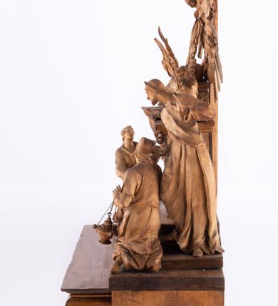 Zdjęcie nr 10: Tabernakulum w formie Arki Przymierza, adorowanej przez dwie klęczące figury św. Jana i starotestamentowego arcykapłana, dwie stojące postacie lewitów oraz klęczących aniołów, zwieńczonej glorią promienistą z okiem Opatrzności. Arka w formie prostopadłościennej szafki z dwoma drążkami do noszenia jest od frontu podzielone na trzy pola: środkowe zamknięte łukiem wklęsło-wypukłym i boczne o ćwierćkoliście wyciętych narożach. Pole środkowe stanowią drzwiczki z rytymi cyframi Dekalogu, a w bocznych znajdują się kłosy zbóż i winne grono. Na skłębionych chmurach z podestem leży baranek. Nad nim widnieje znacznej wielkości gloria promienista z wieńcem chmur i umieszczonym w nim okiem Opatrzności oraz cztery uskrzydlone główki anielskie. Nad parą główek w górnej części papieska tiara ze skrzyżowanymi kluczami. Po bokach baranka dwa klęczące, uskrzydlone nagie aniołki o rękach i nogach utworzonych z piór. Obok arki dwie postacie lewitów ubranych w długie szaty, w różnicowanych pozach i gestach. Poniżej klęczą postacie św. Jana z księgą i orłem obok niego i kapłana w tradycyjnym starotestamentowym stroju – efodzie czyli tunice i płaszczu wierzchnim przepasanym na biodrach, z pektorałem na piersi i czapką na głowie. 