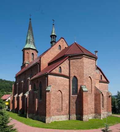 Zdjęcie nr 3: Kościół ceglany z kamiennym przyziemiem, na planie prostokąta z węższym i niższym prezbiterium flankowanym dwoma aneksami wystającymi poza lico nawy i wieżą od zachodu. Kościół orientowany, jednonawowy, czteroprzęsłowy z węższym, jednoprzęsłowym prezbiterium zamkniętym trójbocznie, z kruchtą w przyziemiu wieży. Nawa artykułowana półfilarami o ściętych narożach, przechodzących w gurty krzyżowo-żebrowego sklepienia. W nawie i prezbiterium okna prostokątne zamknięte łukiem ostrym; główne wejście od wschodu. Identyczne okna w aneksach przy prezbiterium. Aneksy dwuprzęsłowe ujęte wielobocznymi filarami, zamknięte trójbocznie z parasolowym sklepieniem. Chór muzyczny w czwartym przęśle nawy, wsparty na wielobocznych filarach z drewnianym parapetem ozdobionym ostrołukowymi blendami. Kruchta węższa od nawy, zasklepiona krzyżowo. Fasada węższa od nawy, ujęta przyporami w narożach, między którymi ostrołukowe wejście. W drugiej kondygnacji oddzielonej parapetem wysokie okno zamknięte łukiem ostrym, nad którym tarcza zegara. Nad fasadą ośmioboczna wieża. W wieży na przemian okna i płyciny, zamknięte łukiem ostrym. Trójboczne prezbiterium w narożach ujęte przyporami sięgającymi połowy wysokości, między którymi ostrołukowe okna. Aneksy na planie prostokąta z przyporami na narożach oraz jedną w części bocznej. Czteroosiowa ściana nawy i naroża oddzielone przyporami, między którymi ostrołukowo zakończone okna. Hełm wieży w formie ośmiobocznego stożka, załamującego się w partii dolnej. Nawa z dwuspadowym dachem z wieżyczką na sygnaturkę nad pierwszym przęsłem.