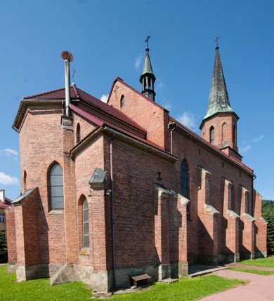 Zdjęcie nr 5: Kościół ceglany z kamiennym przyziemiem, na planie prostokąta z węższym i niższym prezbiterium flankowanym dwoma aneksami wystającymi poza lico nawy i wieżą od zachodu. Kościół orientowany, jednonawowy, czteroprzęsłowy z węższym, jednoprzęsłowym prezbiterium zamkniętym trójbocznie, z kruchtą w przyziemiu wieży. Nawa artykułowana półfilarami o ściętych narożach, przechodzących w gurty krzyżowo-żebrowego sklepienia. W nawie i prezbiterium okna prostokątne zamknięte łukiem ostrym; główne wejście od wschodu. Identyczne okna w aneksach przy prezbiterium. Aneksy dwuprzęsłowe ujęte wielobocznymi filarami, zamknięte trójbocznie z parasolowym sklepieniem. Chór muzyczny w czwartym przęśle nawy, wsparty na wielobocznych filarach z drewnianym parapetem ozdobionym ostrołukowymi blendami. Kruchta węższa od nawy, zasklepiona krzyżowo. Fasada węższa od nawy, ujęta przyporami w narożach, między którymi ostrołukowe wejście. W drugiej kondygnacji oddzielonej parapetem wysokie okno zamknięte łukiem ostrym, nad którym tarcza zegara. Nad fasadą ośmioboczna wieża. W wieży na przemian okna i płyciny, zamknięte łukiem ostrym. Trójboczne prezbiterium w narożach ujęte przyporami sięgającymi połowy wysokości, między którymi ostrołukowe okna. Aneksy na planie prostokąta z przyporami na narożach oraz jedną w części bocznej. Czteroosiowa ściana nawy i naroża oddzielone przyporami, między którymi ostrołukowo zakończone okna. Hełm wieży w formie ośmiobocznego stożka, załamującego się w partii dolnej. Nawa z dwuspadowym dachem z wieżyczką na sygnaturkę nad pierwszym przęsłem.
