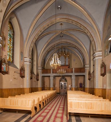 Zdjęcie nr 12: Kościół ceglany z kamiennym przyziemiem, na planie prostokąta z węższym i niższym prezbiterium flankowanym dwoma aneksami wystającymi poza lico nawy i wieżą od zachodu. Kościół orientowany, jednonawowy, czteroprzęsłowy z węższym, jednoprzęsłowym prezbiterium zamkniętym trójbocznie, z kruchtą w przyziemiu wieży. Nawa artykułowana półfilarami o ściętych narożach, przechodzących w gurty krzyżowo-żebrowego sklepienia. W nawie i prezbiterium okna prostokątne zamknięte łukiem ostrym; główne wejście od wschodu. Identyczne okna w aneksach przy prezbiterium. Aneksy dwuprzęsłowe ujęte wielobocznymi filarami, zamknięte trójbocznie z parasolowym sklepieniem. Chór muzyczny w czwartym przęśle nawy, wsparty na wielobocznych filarach z drewnianym parapetem ozdobionym ostrołukowymi blendami. Kruchta węższa od nawy, zasklepiona krzyżowo. Fasada węższa od nawy, ujęta przyporami w narożach, między którymi ostrołukowe wejście. W drugiej kondygnacji oddzielonej parapetem wysokie okno zamknięte łukiem ostrym, nad którym tarcza zegara. Nad fasadą ośmioboczna wieża. W wieży na przemian okna i płyciny, zamknięte łukiem ostrym. Trójboczne prezbiterium w narożach ujęte przyporami sięgającymi połowy wysokości, między którymi ostrołukowe okna. Aneksy na planie prostokąta z przyporami na narożach oraz jedną w części bocznej. Czteroosiowa ściana nawy i naroża oddzielone przyporami, między którymi ostrołukowo zakończone okna. Hełm wieży w formie ośmiobocznego stożka, załamującego się w partii dolnej. Nawa z dwuspadowym dachem z wieżyczką na sygnaturkę nad pierwszym przęsłem.