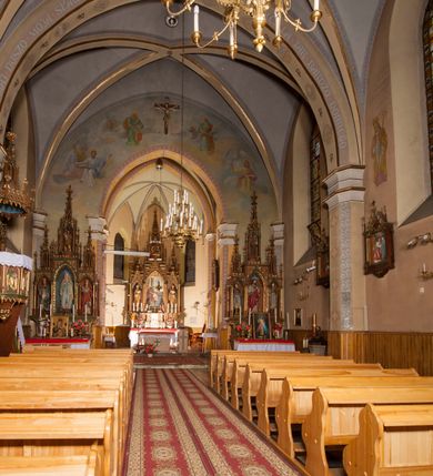 Zdjęcie nr 8: Kościół ceglany z kamiennym przyziemiem, na planie prostokąta z węższym i niższym prezbiterium flankowanym dwoma aneksami wystającymi poza lico nawy i wieżą od zachodu. Kościół orientowany, jednonawowy, czteroprzęsłowy z węższym, jednoprzęsłowym prezbiterium zamkniętym trójbocznie, z kruchtą w przyziemiu wieży. Nawa artykułowana półfilarami o ściętych narożach, przechodzących w gurty krzyżowo-żebrowego sklepienia. W nawie i prezbiterium okna prostokątne zamknięte łukiem ostrym; główne wejście od wschodu. Identyczne okna w aneksach przy prezbiterium. Aneksy dwuprzęsłowe ujęte wielobocznymi filarami, zamknięte trójbocznie z parasolowym sklepieniem. Chór muzyczny w czwartym przęśle nawy, wsparty na wielobocznych filarach z drewnianym parapetem ozdobionym ostrołukowymi blendami. Kruchta węższa od nawy, zasklepiona krzyżowo. Fasada węższa od nawy, ujęta przyporami w narożach, między którymi ostrołukowe wejście. W drugiej kondygnacji oddzielonej parapetem wysokie okno zamknięte łukiem ostrym, nad którym tarcza zegara. Nad fasadą ośmioboczna wieża. W wieży na przemian okna i płyciny, zamknięte łukiem ostrym. Trójboczne prezbiterium w narożach ujęte przyporami sięgającymi połowy wysokości, między którymi ostrołukowe okna. Aneksy na planie prostokąta z przyporami na narożach oraz jedną w części bocznej. Czteroosiowa ściana nawy i naroża oddzielone przyporami, między którymi ostrołukowo zakończone okna. Hełm wieży w formie ośmiobocznego stożka, załamującego się w partii dolnej. Nawa z dwuspadowym dachem z wieżyczką na sygnaturkę nad pierwszym przęsłem.