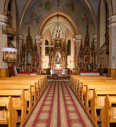 Zdjęcie nr 6: Kościół ceglany z kamiennym przyziemiem, na planie prostokąta z węższym i niższym prezbiterium flankowanym dwoma aneksami wystającymi poza lico nawy i wieżą od zachodu. Kościół orientowany, jednonawowy, czteroprzęsłowy z węższym, jednoprzęsłowym prezbiterium zamkniętym trójbocznie, z kruchtą w przyziemiu wieży. Nawa artykułowana półfilarami o ściętych narożach, przechodzących w gurty krzyżowo-żebrowego sklepienia. W nawie i prezbiterium okna prostokątne zamknięte łukiem ostrym; główne wejście od wschodu. Identyczne okna w aneksach przy prezbiterium. Aneksy dwuprzęsłowe ujęte wielobocznymi filarami, zamknięte trójbocznie z parasolowym sklepieniem. Chór muzyczny w czwartym przęśle nawy, wsparty na wielobocznych filarach z drewnianym parapetem ozdobionym ostrołukowymi blendami. Kruchta węższa od nawy, zasklepiona krzyżowo. Fasada węższa od nawy, ujęta przyporami w narożach, między którymi ostrołukowe wejście. W drugiej kondygnacji oddzielonej parapetem wysokie okno zamknięte łukiem ostrym, nad którym tarcza zegara. Nad fasadą ośmioboczna wieża. W wieży na przemian okna i płyciny, zamknięte łukiem ostrym. Trójboczne prezbiterium w narożach ujęte przyporami sięgającymi połowy wysokości, między którymi ostrołukowe okna. Aneksy na planie prostokąta z przyporami na narożach oraz jedną w części bocznej. Czteroosiowa ściana nawy i naroża oddzielone przyporami, między którymi ostrołukowo zakończone okna. Hełm wieży w formie ośmiobocznego stożka, załamującego się w partii dolnej. Nawa z dwuspadowym dachem z wieżyczką na sygnaturkę nad pierwszym przęsłem.