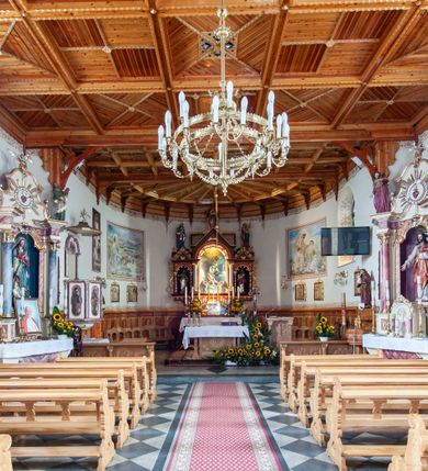 Zdjęcie nr 9: Kościół św. Rozalii w Podszklu usytuowany jest przy skrzyżowaniu dróg w centrum miejscowości na obszernym placu, na którym rosną stare jesiony. Teren przykościelny ogrodzony jest kamiennym murem z czterema murowanymi z nieregularnych kamieni kaplicami rozmieszczonymi na jego obwodzie. Wejście na teren przykościelny prowadzi przez trzy bramy umieszczone od strony północnej, każda flankowana jest przez parę obelisków. Kolejne wejście znajduje się od strony zachodniej. 

Kościół orientowany z krótkim zakończonym półkoliście prezbiterium i czworoboczną wieżą od zachodu. Do prezbiterium jest dobudowana zakrystia. Główne wejście do świątyni od strony zachodniej, drugie przez zakrystię. Od południa dobudowana została nowsza przybudówka. Nawa szersza od prezbiterium założona na planie prostokąta. Wnętrze nakryte jest drewnianym stropem z kasetonami. Nawę oświetlają pary okien na każdej ze ścian w kształcie stojących prostokątów, zamkniętych półkoliście; do prezbiterium zaś światło wpada przez okno umieszczone od strony południowej oraz mniejszy oculus na ścieni wschodniej. Chór muzyczny drewniany, wsparty na dwóch drewnianych słupach, z dostępem schodami od południowej strony nawy.

Elewacja zewnętrzna pozbawiona większych podziałów architektonicznych z wyjątkiem podokapowych gzymsów, w partii cokołowej okładzina kamienna z regularnych ciosów, wyżej kościół otynkowany. W fasadzie trójkondygnacyjna, czworoboczna wieża o zaokrąglonych narożnikach, w jednej trzeciej wysokości oddzielona daszkiem. W drugiej i trzeciej kondygnacji podziały zaznaczone jedynie przez pojedyncze otwory okienne na każdej ze ścian i kondygnacji w kształcie stojących prostokątów, zamkniętych półkoliście. Wieża nakryta ostrosłupowym hełmem. Po bokach flankowana jest przez dwie przybudówki na planie ćwierćkoła, sięgające wysokością do drugiej kondygnacji wieży. Nawę i prezbiterium nakrywa jednokalenicowy, stromy dach, pokryty blachą. Na skrzyżowaniu nawy z prezbiterium wieżyczka na sygnaturkę z latarnią. Wejście do kościoła od zachodu zaakcentowane jest dwuspadowym daszkiem z trójkątnym szczytem oraz małą wieżyczką z cebulastym hełmem.