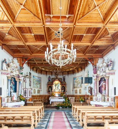 Zdjęcie nr 8: Kościół św. Rozalii w Podszklu usytuowany jest przy skrzyżowaniu dróg w centrum miejscowości na obszernym placu, na którym rosną stare jesiony. Teren przykościelny ogrodzony jest kamiennym murem z czterema murowanymi z nieregularnych kamieni kaplicami rozmieszczonymi na jego obwodzie. Wejście na teren przykościelny prowadzi przez trzy bramy umieszczone od strony północnej, każda flankowana jest przez parę obelisków. Kolejne wejście znajduje się od strony zachodniej. 

Kościół orientowany z krótkim zakończonym półkoliście prezbiterium i czworoboczną wieżą od zachodu. Do prezbiterium jest dobudowana zakrystia. Główne wejście do świątyni od strony zachodniej, drugie przez zakrystię. Od południa dobudowana została nowsza przybudówka. Nawa szersza od prezbiterium założona na planie prostokąta. Wnętrze nakryte jest drewnianym stropem z kasetonami. Nawę oświetlają pary okien na każdej ze ścian w kształcie stojących prostokątów, zamkniętych półkoliście; do prezbiterium zaś światło wpada przez okno umieszczone od strony południowej oraz mniejszy oculus na ścieni wschodniej. Chór muzyczny drewniany, wsparty na dwóch drewnianych słupach, z dostępem schodami od południowej strony nawy.

Elewacja zewnętrzna pozbawiona większych podziałów architektonicznych z wyjątkiem podokapowych gzymsów, w partii cokołowej okładzina kamienna z regularnych ciosów, wyżej kościół otynkowany. W fasadzie trójkondygnacyjna, czworoboczna wieża o zaokrąglonych narożnikach, w jednej trzeciej wysokości oddzielona daszkiem. W drugiej i trzeciej kondygnacji podziały zaznaczone jedynie przez pojedyncze otwory okienne na każdej ze ścian i kondygnacji w kształcie stojących prostokątów, zamkniętych półkoliście. Wieża nakryta ostrosłupowym hełmem. Po bokach flankowana jest przez dwie przybudówki na planie ćwierćkoła, sięgające wysokością do drugiej kondygnacji wieży. Nawę i prezbiterium nakrywa jednokalenicowy, stromy dach, pokryty blachą. Na skrzyżowaniu nawy z prezbiterium wieżyczka na sygnaturkę z latarnią. Wejście do kościoła od zachodu zaakcentowane jest dwuspadowym daszkiem z trójkątnym szczytem oraz małą wieżyczką z cebulastym hełmem.