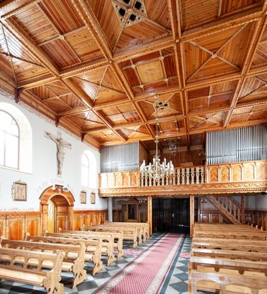 Zdjęcie nr 12: Kościół św. Rozalii w Podszklu usytuowany jest przy skrzyżowaniu dróg w centrum miejscowości na obszernym placu, na którym rosną stare jesiony. Teren przykościelny ogrodzony jest kamiennym murem z czterema murowanymi z nieregularnych kamieni kaplicami rozmieszczonymi na jego obwodzie. Wejście na teren przykościelny prowadzi przez trzy bramy umieszczone od strony północnej, każda flankowana jest przez parę obelisków. Kolejne wejście znajduje się od strony zachodniej. 

Kościół orientowany z krótkim zakończonym półkoliście prezbiterium i czworoboczną wieżą od zachodu. Do prezbiterium jest dobudowana zakrystia. Główne wejście do świątyni od strony zachodniej, drugie przez zakrystię. Od południa dobudowana została nowsza przybudówka. Nawa szersza od prezbiterium założona na planie prostokąta. Wnętrze nakryte jest drewnianym stropem z kasetonami. Nawę oświetlają pary okien na każdej ze ścian w kształcie stojących prostokątów, zamkniętych półkoliście; do prezbiterium zaś światło wpada przez okno umieszczone od strony południowej oraz mniejszy oculus na ścieni wschodniej. Chór muzyczny drewniany, wsparty na dwóch drewnianych słupach, z dostępem schodami od południowej strony nawy.

Elewacja zewnętrzna pozbawiona większych podziałów architektonicznych z wyjątkiem podokapowych gzymsów, w partii cokołowej okładzina kamienna z regularnych ciosów, wyżej kościół otynkowany. W fasadzie trójkondygnacyjna, czworoboczna wieża o zaokrąglonych narożnikach, w jednej trzeciej wysokości oddzielona daszkiem. W drugiej i trzeciej kondygnacji podziały zaznaczone jedynie przez pojedyncze otwory okienne na każdej ze ścian i kondygnacji w kształcie stojących prostokątów, zamkniętych półkoliście. Wieża nakryta ostrosłupowym hełmem. Po bokach flankowana jest przez dwie przybudówki na planie ćwierćkoła, sięgające wysokością do drugiej kondygnacji wieży. Nawę i prezbiterium nakrywa jednokalenicowy, stromy dach, pokryty blachą. Na skrzyżowaniu nawy z prezbiterium wieżyczka na sygnaturkę z latarnią. Wejście do kościoła od zachodu zaakcentowane jest dwuspadowym daszkiem z trójkątnym szczytem oraz małą wieżyczką z cebulastym hełmem.