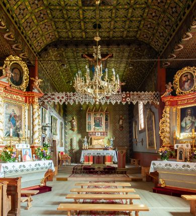Zdjęcie nr 34: Kościół jednonawowy,  prezbiterium oddzielone ścianą tęczową z poprzeczną belką. Stropy pokryte dekoracją malarską imitującą kasetony z rozetami, z przedstawieniem Matki Boskiej z Dzieciątkiem w prezbiterium, św. Michała Archanioła w nawie oraz klęczących aniołów na ścianach. W dolnej partii ściany niebieskie, z biegnącą dookoła inskrypcją, a do jednej trzeciej wysokości od dołu w kolorze drewna. W przedsionku polichromia patronowa o motywach geometrycznych, roślinnych, zwierzęcych itd.  W nawie od zachodu chór muzyczny z dekoracją malarską roślinną i antropomorficzną. Nawa i prezbiterium naryte pozornym sklepieniem w kształcie spłaszczonej kolebki ze skośnymi fasetami. W nawie głównej jedno duże okno w kształcie stojącego prostokąta, bliżej chóru drugie, niewielkie, w kształcie leżącego; kolejne w wieży, przedsionku i prezbiterium. Główne wejście od zachodu, drugie przez kruchtę od południa, trzecie do zakrystii. Portal południowy prostokątny, osłonięty daszkiem, poniżej trójkątnego szczytu wypełnionego oknem. Od zachodu kwadratowa wieża o pochyłych ścianach pobitych gontem, z nadwieszoną, nieco występującą izbicą szalowaną pionowymi deskami, na dolnych końcach ozdobnie wycinanymi. Ściany obłożone gontem, gładkie. Nad nawą i prezbiterium dach jednokalenicowy, gontowy, wieża z ostrosłupowym hełmem. Nad nawą barokowa wieżyczka na sygnaturkę kryta blachą. 
Najcenniejszym elementem wyposażenia jest gotyckie retabulum ołtarzowe pełniące od 1935 roku rolę ołtarza głównego w miejsce rozebranego, barokowego. Oprócz niego szczególne znaczenie mają fragmenty zachowanej polichromii patronowej z około 1500 roku. 
