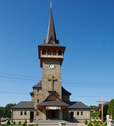 Zdjęcie nr 1: Kościół orientowany, trójnawowy, z niższym i węższym prezbiterium zakończonym absydą. Przy prezbiterium od strony południowej dostawiona kaplica na rzucie prostokąta, od północny analogiczna zakrystia, oba pomieszczenia nakryte dachami czterospadowymi. Do nawy od południa, na wysokości drugiego przęsła dostawiona zadaszona kruchta  wsparta na dwóch kamiennych filarach. Do elewacji zachodniej od południa i północy dostawione dwa aneksy na rzucie prostokąta nakryte dachami czterospadowymi. Nawa główna trójprzęsłowa, znacznie wyższa i szersza od naw bocznych, kryta stropem wspartym na murowanych z cegieł filarach o kompozytowych kapitelach. Doświetlona prostokątnymi oknami zamkniętymi łukiem półkolistym o podziale naśladującym triforium. Nawy boczne wydzielone od głównej półkolistymi arkadami, doświetlone okami w kształcie stojącego prostokąta zamkniętego półkoliście. Prezbiterium kryte prostym stropem oddzielone od nawy ścianą tęczową z półkolistą arkadą z profilowaną archiwoltą. Doświetlone wąskimi oknami w kształcie stojącego prostokąta zamkniętego łukiem półkolistym. Analogiczne okna w kaplicy południowej. W fasadzie czworoboczna zwężająca się ku górze wieża z drewnianą hurdycją, nakryta ostrosłupowym dachem zwieńczonym krzyżem. W przyziemiu portal nakryty wspartym na dwóch kamiennych filarach dachem półszczytowym. Powyżej prosty, drewniany krzyż oraz okrągła płycina mieszcząca tarczę zegarową. Elewacje licowane kamieniem, od południa i północy murowane z czerwonej cegły z kamiennymi obramieniami wokół okien. Dachy kryte blachą, ponad prezbiterium czworoboczna wieżyczka na sygnaturkę zwieńczona ostrosłupowym hełmem.