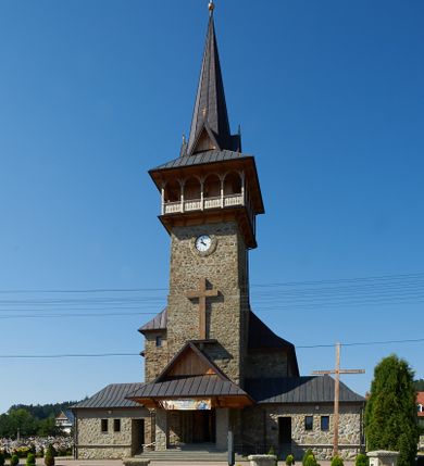 Zdjęcie nr 5: Kościół orientowany, trójnawowy, z niższym i węższym prezbiterium zakończonym absydą. Przy prezbiterium od strony południowej dostawiona kaplica na rzucie prostokąta, od północny analogiczna zakrystia, oba pomieszczenia nakryte dachami czterospadowymi. Do nawy od południa, na wysokości drugiego przęsła dostawiona zadaszona kruchta  wsparta na dwóch kamiennych filarach. Do elewacji zachodniej od południa i północy dostawione dwa aneksy na rzucie prostokąta nakryte dachami czterospadowymi. Nawa główna trójprzęsłowa, znacznie wyższa i szersza od naw bocznych, kryta stropem wspartym na murowanych z cegieł filarach o kompozytowych kapitelach. Doświetlona prostokątnymi oknami zamkniętymi łukiem półkolistym o podziale naśladującym triforium. Nawy boczne wydzielone od głównej półkolistymi arkadami, doświetlone okami w kształcie stojącego prostokąta zamkniętego półkoliście. Prezbiterium kryte prostym stropem oddzielone od nawy ścianą tęczową z półkolistą arkadą z profilowaną archiwoltą. Doświetlone wąskimi oknami w kształcie stojącego prostokąta zamkniętego łukiem półkolistym. Analogiczne okna w kaplicy południowej. W fasadzie czworoboczna zwężająca się ku górze wieża z drewnianą hurdycją, nakryta ostrosłupowym dachem zwieńczonym krzyżem. W przyziemiu portal nakryty wspartym na dwóch kamiennych filarach dachem półszczytowym. Powyżej prosty, drewniany krzyż oraz okrągła płycina mieszcząca tarczę zegarową. Elewacje licowane kamieniem, od południa i północy murowane z czerwonej cegły z kamiennymi obramieniami wokół okien. Dachy kryte blachą, ponad prezbiterium czworoboczna wieżyczka na sygnaturkę zwieńczona ostrosłupowym hełmem.