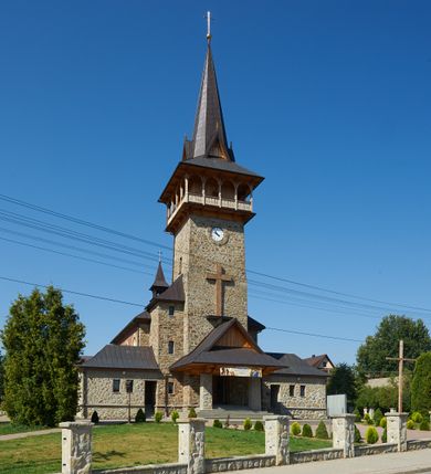 Zdjęcie nr 4: Kościół orientowany, trójnawowy, z niższym i węższym prezbiterium zakończonym absydą. Przy prezbiterium od strony południowej dostawiona kaplica na rzucie prostokąta, od północny analogiczna zakrystia, oba pomieszczenia nakryte dachami czterospadowymi. Do nawy od południa, na wysokości drugiego przęsła dostawiona zadaszona kruchta  wsparta na dwóch kamiennych filarach. Do elewacji zachodniej od południa i północy dostawione dwa aneksy na rzucie prostokąta nakryte dachami czterospadowymi. Nawa główna trójprzęsłowa, znacznie wyższa i szersza od naw bocznych, kryta stropem wspartym na murowanych z cegieł filarach o kompozytowych kapitelach. Doświetlona prostokątnymi oknami zamkniętymi łukiem półkolistym o podziale naśladującym triforium. Nawy boczne wydzielone od głównej półkolistymi arkadami, doświetlone okami w kształcie stojącego prostokąta zamkniętego półkoliście. Prezbiterium kryte prostym stropem oddzielone od nawy ścianą tęczową z półkolistą arkadą z profilowaną archiwoltą. Doświetlone wąskimi oknami w kształcie stojącego prostokąta zamkniętego łukiem półkolistym. Analogiczne okna w kaplicy południowej. W fasadzie czworoboczna zwężająca się ku górze wieża z drewnianą hurdycją, nakryta ostrosłupowym dachem zwieńczonym krzyżem. W przyziemiu portal nakryty wspartym na dwóch kamiennych filarach dachem półszczytowym. Powyżej prosty, drewniany krzyż oraz okrągła płycina mieszcząca tarczę zegarową. Elewacje licowane kamieniem, od południa i północy murowane z czerwonej cegły z kamiennymi obramieniami wokół okien. Dachy kryte blachą, ponad prezbiterium czworoboczna wieżyczka na sygnaturkę zwieńczona ostrosłupowym hełmem.