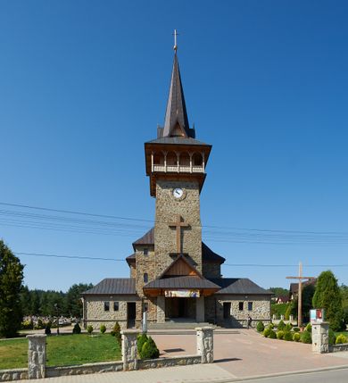 Zdjęcie nr 2: Kościół orientowany, trójnawowy, z niższym i węższym prezbiterium zakończonym absydą. Przy prezbiterium od strony południowej dostawiona kaplica na rzucie prostokąta, od północny analogiczna zakrystia, oba pomieszczenia nakryte dachami czterospadowymi. Do nawy od południa, na wysokości drugiego przęsła dostawiona zadaszona kruchta  wsparta na dwóch kamiennych filarach. Do elewacji zachodniej od południa i północy dostawione dwa aneksy na rzucie prostokąta nakryte dachami czterospadowymi. Nawa główna trójprzęsłowa, znacznie wyższa i szersza od naw bocznych, kryta stropem wspartym na murowanych z cegieł filarach o kompozytowych kapitelach. Doświetlona prostokątnymi oknami zamkniętymi łukiem półkolistym o podziale naśladującym triforium. Nawy boczne wydzielone od głównej półkolistymi arkadami, doświetlone okami w kształcie stojącego prostokąta zamkniętego półkoliście. Prezbiterium kryte prostym stropem oddzielone od nawy ścianą tęczową z półkolistą arkadą z profilowaną archiwoltą. Doświetlone wąskimi oknami w kształcie stojącego prostokąta zamkniętego łukiem półkolistym. Analogiczne okna w kaplicy południowej. W fasadzie czworoboczna zwężająca się ku górze wieża z drewnianą hurdycją, nakryta ostrosłupowym dachem zwieńczonym krzyżem. W przyziemiu portal nakryty wspartym na dwóch kamiennych filarach dachem półszczytowym. Powyżej prosty, drewniany krzyż oraz okrągła płycina mieszcząca tarczę zegarową. Elewacje licowane kamieniem, od południa i północy murowane z czerwonej cegły z kamiennymi obramieniami wokół okien. Dachy kryte blachą, ponad prezbiterium czworoboczna wieżyczka na sygnaturkę zwieńczona ostrosłupowym hełmem.