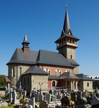 Zdjęcie nr 9: Kościół orientowany, trójnawowy, z niższym i węższym prezbiterium zakończonym absydą. Przy prezbiterium od strony południowej dostawiona kaplica na rzucie prostokąta, od północny analogiczna zakrystia, oba pomieszczenia nakryte dachami czterospadowymi. Do nawy od południa, na wysokości drugiego przęsła dostawiona zadaszona kruchta  wsparta na dwóch kamiennych filarach. Do elewacji zachodniej od południa i północy dostawione dwa aneksy na rzucie prostokąta nakryte dachami czterospadowymi. Nawa główna trójprzęsłowa, znacznie wyższa i szersza od naw bocznych, kryta stropem wspartym na murowanych z cegieł filarach o kompozytowych kapitelach. Doświetlona prostokątnymi oknami zamkniętymi łukiem półkolistym o podziale naśladującym triforium. Nawy boczne wydzielone od głównej półkolistymi arkadami, doświetlone okami w kształcie stojącego prostokąta zamkniętego półkoliście. Prezbiterium kryte prostym stropem oddzielone od nawy ścianą tęczową z półkolistą arkadą z profilowaną archiwoltą. Doświetlone wąskimi oknami w kształcie stojącego prostokąta zamkniętego łukiem półkolistym. Analogiczne okna w kaplicy południowej. W fasadzie czworoboczna zwężająca się ku górze wieża z drewnianą hurdycją, nakryta ostrosłupowym dachem zwieńczonym krzyżem. W przyziemiu portal nakryty wspartym na dwóch kamiennych filarach dachem półszczytowym. Powyżej prosty, drewniany krzyż oraz okrągła płycina mieszcząca tarczę zegarową. Elewacje licowane kamieniem, od południa i północy murowane z czerwonej cegły z kamiennymi obramieniami wokół okien. Dachy kryte blachą, ponad prezbiterium czworoboczna wieżyczka na sygnaturkę zwieńczona ostrosłupowym hełmem.