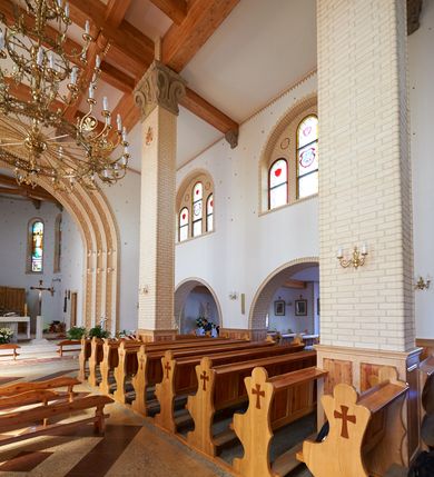 Zdjęcie nr 3: Kościół orientowany, trójnawowy, z niższym i węższym prezbiterium zakończonym absydą. Przy prezbiterium od strony południowej dostawiona kaplica na rzucie prostokąta, od północny analogiczna zakrystia, oba pomieszczenia nakryte dachami czterospadowymi. Do nawy od południa, na wysokości drugiego przęsła dostawiona zadaszona kruchta  wsparta na dwóch kamiennych filarach. Do elewacji zachodniej od południa i północy dostawione dwa aneksy na rzucie prostokąta nakryte dachami czterospadowymi. Nawa główna trójprzęsłowa, znacznie wyższa i szersza od naw bocznych, kryta stropem wspartym na murowanych z cegieł filarach o kompozytowych kapitelach. Doświetlona prostokątnymi oknami zamkniętymi łukiem półkolistym o podziale naśladującym triforium. Nawy boczne wydzielone od głównej półkolistymi arkadami, doświetlone okami w kształcie stojącego prostokąta zamkniętego półkoliście. Prezbiterium kryte prostym stropem oddzielone od nawy ścianą tęczową z półkolistą arkadą z profilowaną archiwoltą. Doświetlone wąskimi oknami w kształcie stojącego prostokąta zamkniętego łukiem półkolistym. Analogiczne okna w kaplicy południowej. W fasadzie czworoboczna zwężająca się ku górze wieża z drewnianą hurdycją, nakryta ostrosłupowym dachem zwieńczonym krzyżem. W przyziemiu portal nakryty wspartym na dwóch kamiennych filarach dachem półszczytowym. Powyżej prosty, drewniany krzyż oraz okrągła płycina mieszcząca tarczę zegarową. Elewacje licowane kamieniem, od południa i północy murowane z czerwonej cegły z kamiennymi obramieniami wokół okien. Dachy kryte blachą, ponad prezbiterium czworoboczna wieżyczka na sygnaturkę zwieńczona ostrosłupowym hełmem.