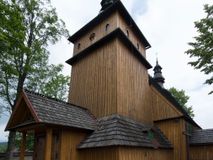 Zdjęcie nr 1: Kościół jest orientowany, drewniany, wzniesiony w konstrukcji zrębowej, o ścianach oszalowanych pionowo, z listwowaniem. Do korpusu nawowego, na rzucie zbliżonym do kwadratu, od wschodu przylega węższe, kwadratowe prezbiterium z dwukondygnacyjną zakrystią ze skarbcem od północy. Od zachodu do korpusu dobudowana jest wieża o konstrukcji słupowo-ramowej i pochyłych ścianach, z przedsionkiem w przyziemiu oraz z pozorną izbicą. Otoczona jest szalowanymi sobotami. Do wieży od zachodu i do korpusu od południa przylegają kruchty. Wnętrze przekryte jest stropami, w nawie z zaskrzynieniami. 
Korpus nawowy, prezbiterium i kruchty nakryte dachami dwuspadowymi, soboty pulpitowymi. Wszystkie dachy kryte gontem. Wieżę wieńczy baniasty hełm, kalenicę nad korpusem sygnaturka z latarnią. 
Ściany wnętrza zdobi figuralno-ornamentalna polichromia. Po zachodniej stronie korpusu nawowego usytuowany jest chór muzyczny wsparty na dwóch kolumnach.
Plac przykościelny otoczony jest murowanym ogrodzeniem oraz wieńcem starych lip.  
