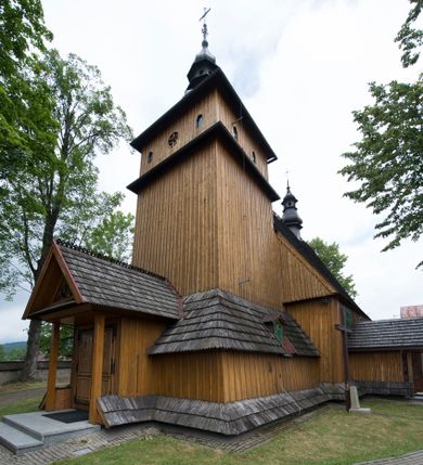 Zdjęcie nr 2: Kościół jest orientowany, drewniany, wzniesiony w konstrukcji zrębowej, o ścianach oszalowanych pionowo, z listwowaniem. Do korpusu nawowego, na rzucie zbliżonym do kwadratu, od wschodu przylega węższe, kwadratowe prezbiterium z dwukondygnacyjną zakrystią ze skarbcem od północy. Od zachodu do korpusu dobudowana jest wieża o konstrukcji słupowo-ramowej i pochyłych ścianach, z przedsionkiem w przyziemiu oraz z pozorną izbicą. Otoczona jest szalowanymi sobotami. Do wieży od zachodu i do korpusu od południa przylegają kruchty. Wnętrze przekryte jest stropami, w nawie z zaskrzynieniami. 
Korpus nawowy, prezbiterium i kruchty nakryte dachami dwuspadowymi, soboty pulpitowymi. Wszystkie dachy kryte gontem. Wieżę wieńczy baniasty hełm, kalenicę nad korpusem sygnaturka z latarnią. 
Ściany wnętrza zdobi figuralno-ornamentalna polichromia. Po zachodniej stronie korpusu nawowego usytuowany jest chór muzyczny wsparty na dwóch kolumnach.
Plac przykościelny otoczony jest murowanym ogrodzeniem oraz wieńcem starych lip.  
