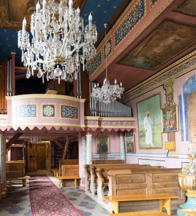 Zdjęcie nr 5: Kościół jest orientowany, drewniany, wzniesiony w konstrukcji zrębowej, o ścianach oszalowanych pionowo, z listwowaniem. Do korpusu nawowego, na rzucie zbliżonym do kwadratu, od wschodu przylega węższe, kwadratowe prezbiterium z dwukondygnacyjną zakrystią ze skarbcem od północy. Od zachodu do korpusu dobudowana jest wieża o konstrukcji słupowo-ramowej i pochyłych ścianach, z przedsionkiem w przyziemiu oraz z pozorną izbicą. Otoczona jest szalowanymi sobotami. Do wieży od zachodu i do korpusu od południa przylegają kruchty. Wnętrze przekryte jest stropami, w nawie z zaskrzynieniami. 
Korpus nawowy, prezbiterium i kruchty nakryte dachami dwuspadowymi, soboty pulpitowymi. Wszystkie dachy kryte gontem. Wieżę wieńczy baniasty hełm, kalenicę nad korpusem sygnaturka z latarnią. 
Ściany wnętrza zdobi figuralno-ornamentalna polichromia. Po zachodniej stronie korpusu nawowego usytuowany jest chór muzyczny wsparty na dwóch kolumnach.
Plac przykościelny otoczony jest murowanym ogrodzeniem oraz wieńcem starych lip.  
