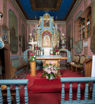 Zdjęcie nr 14: Kościół jest orientowany, drewniany, wzniesiony w konstrukcji zrębowej, o ścianach oszalowanych pionowo, z listwowaniem. Do korpusu nawowego, na rzucie zbliżonym do kwadratu, od wschodu przylega węższe, kwadratowe prezbiterium z dwukondygnacyjną zakrystią ze skarbcem od północy. Od zachodu do korpusu dobudowana jest wieża o konstrukcji słupowo-ramowej i pochyłych ścianach, z przedsionkiem w przyziemiu oraz z pozorną izbicą. Otoczona jest szalowanymi sobotami. Do wieży od zachodu i do korpusu od południa przylegają kruchty. Wnętrze przekryte jest stropami, w nawie z zaskrzynieniami. 
Korpus nawowy, prezbiterium i kruchty nakryte dachami dwuspadowymi, soboty pulpitowymi. Wszystkie dachy kryte gontem. Wieżę wieńczy baniasty hełm, kalenicę nad korpusem sygnaturka z latarnią. 
Ściany wnętrza zdobi figuralno-ornamentalna polichromia. Po zachodniej stronie korpusu nawowego usytuowany jest chór muzyczny wsparty na dwóch kolumnach.
Plac przykościelny otoczony jest murowanym ogrodzeniem oraz wieńcem starych lip.  
