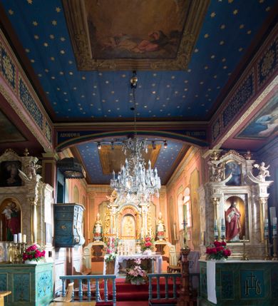 Zdjęcie nr 11: Kościół jest orientowany, drewniany, wzniesiony w konstrukcji zrębowej, o ścianach oszalowanych pionowo, z listwowaniem. Do korpusu nawowego, na rzucie zbliżonym do kwadratu, od wschodu przylega węższe, kwadratowe prezbiterium z dwukondygnacyjną zakrystią ze skarbcem od północy. Od zachodu do korpusu dobudowana jest wieża o konstrukcji słupowo-ramowej i pochyłych ścianach, z przedsionkiem w przyziemiu oraz z pozorną izbicą. Otoczona jest szalowanymi sobotami. Do wieży od zachodu i do korpusu od południa przylegają kruchty. Wnętrze przekryte jest stropami, w nawie z zaskrzynieniami. 
Korpus nawowy, prezbiterium i kruchty nakryte dachami dwuspadowymi, soboty pulpitowymi. Wszystkie dachy kryte gontem. Wieżę wieńczy baniasty hełm, kalenicę nad korpusem sygnaturka z latarnią. 
Ściany wnętrza zdobi figuralno-ornamentalna polichromia. Po zachodniej stronie korpusu nawowego usytuowany jest chór muzyczny wsparty na dwóch kolumnach.
Plac przykościelny otoczony jest murowanym ogrodzeniem oraz wieńcem starych lip.  
