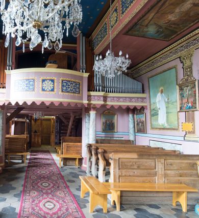 Zdjęcie nr 4: Kościół jest orientowany, drewniany, wzniesiony w konstrukcji zrębowej, o ścianach oszalowanych pionowo, z listwowaniem. Do korpusu nawowego, na rzucie zbliżonym do kwadratu, od wschodu przylega węższe, kwadratowe prezbiterium z dwukondygnacyjną zakrystią ze skarbcem od północy. Od zachodu do korpusu dobudowana jest wieża o konstrukcji słupowo-ramowej i pochyłych ścianach, z przedsionkiem w przyziemiu oraz z pozorną izbicą. Otoczona jest szalowanymi sobotami. Do wieży od zachodu i do korpusu od południa przylegają kruchty. Wnętrze przekryte jest stropami, w nawie z zaskrzynieniami. 
Korpus nawowy, prezbiterium i kruchty nakryte dachami dwuspadowymi, soboty pulpitowymi. Wszystkie dachy kryte gontem. Wieżę wieńczy baniasty hełm, kalenicę nad korpusem sygnaturka z latarnią. 
Ściany wnętrza zdobi figuralno-ornamentalna polichromia. Po zachodniej stronie korpusu nawowego usytuowany jest chór muzyczny wsparty na dwóch kolumnach.
Plac przykościelny otoczony jest murowanym ogrodzeniem oraz wieńcem starych lip.  
